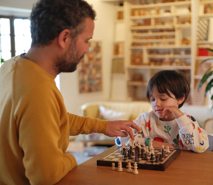 Un père et son fils jouent aux échecs en bois à la maison