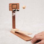 Main lançant la bille vers le panier en bois du basket