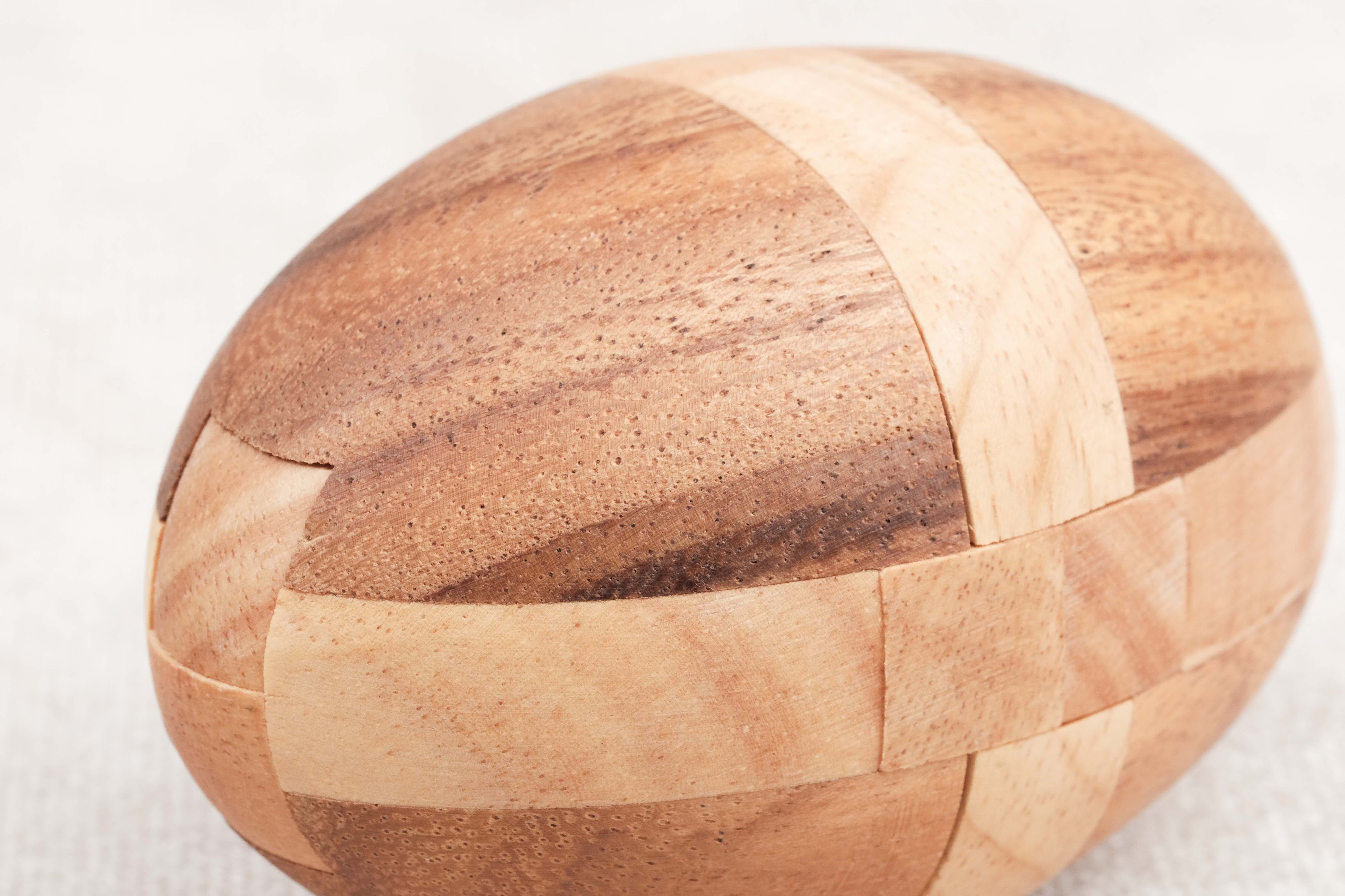 Zoom texture : Gros plan sur le Ballon de Rugby en bois montrant les détails des pièces imbriquées.