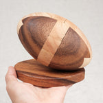 Prise en main : Ballon de Rugby en bois sur socle tenu dans une main, taille L.