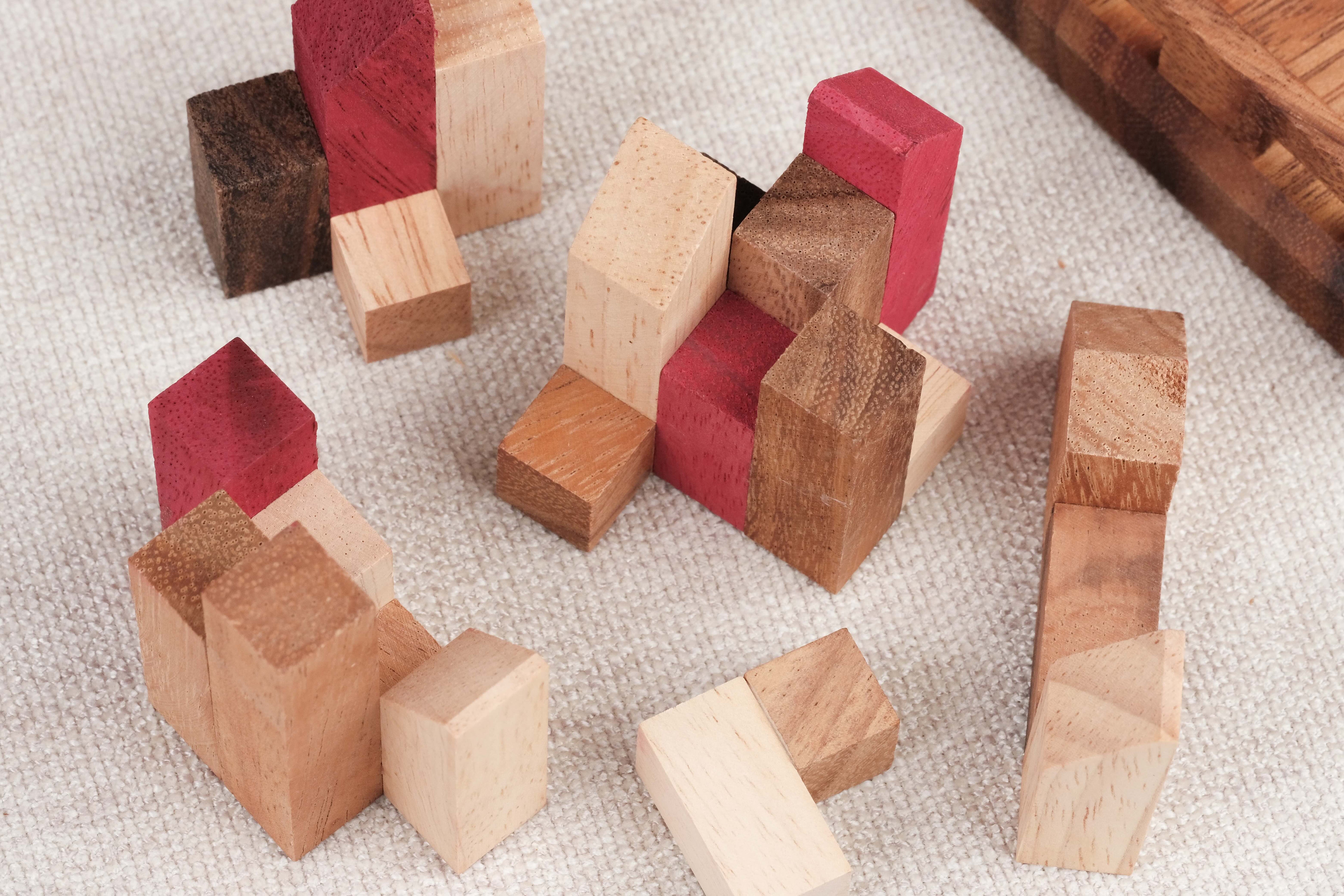Gros plan sur les pièces colorées du casse-tête La Cité Infernale en bois imbriquées dans la base – Puzzle multi-combinaisons – Jeux Faugère