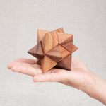 Casse-tête La Star en bois, format 8 cm, tenu dans la main.