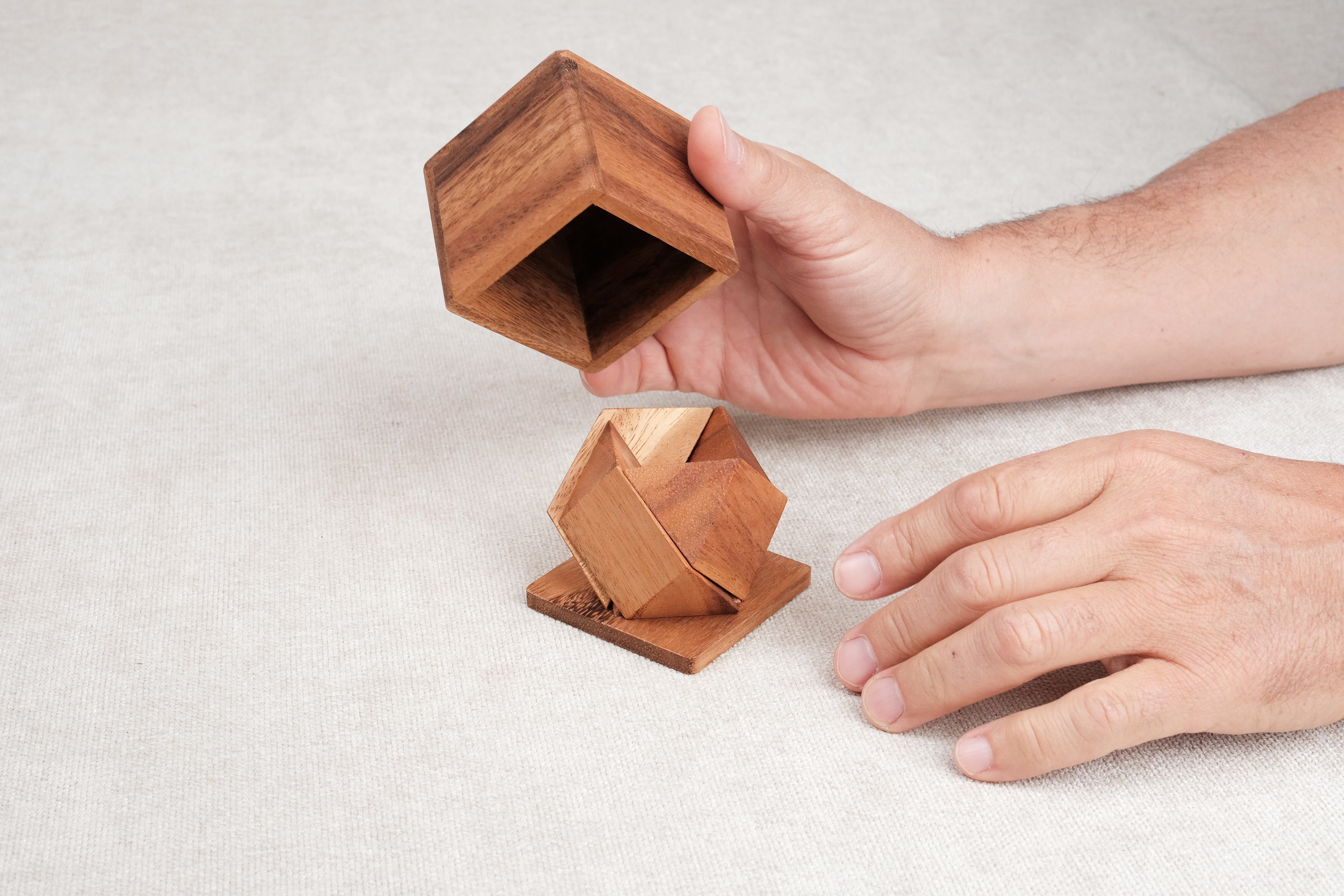 Casse-tête Pyramides en Boîte – manipulation des pièces et de la boîte en bois par une main