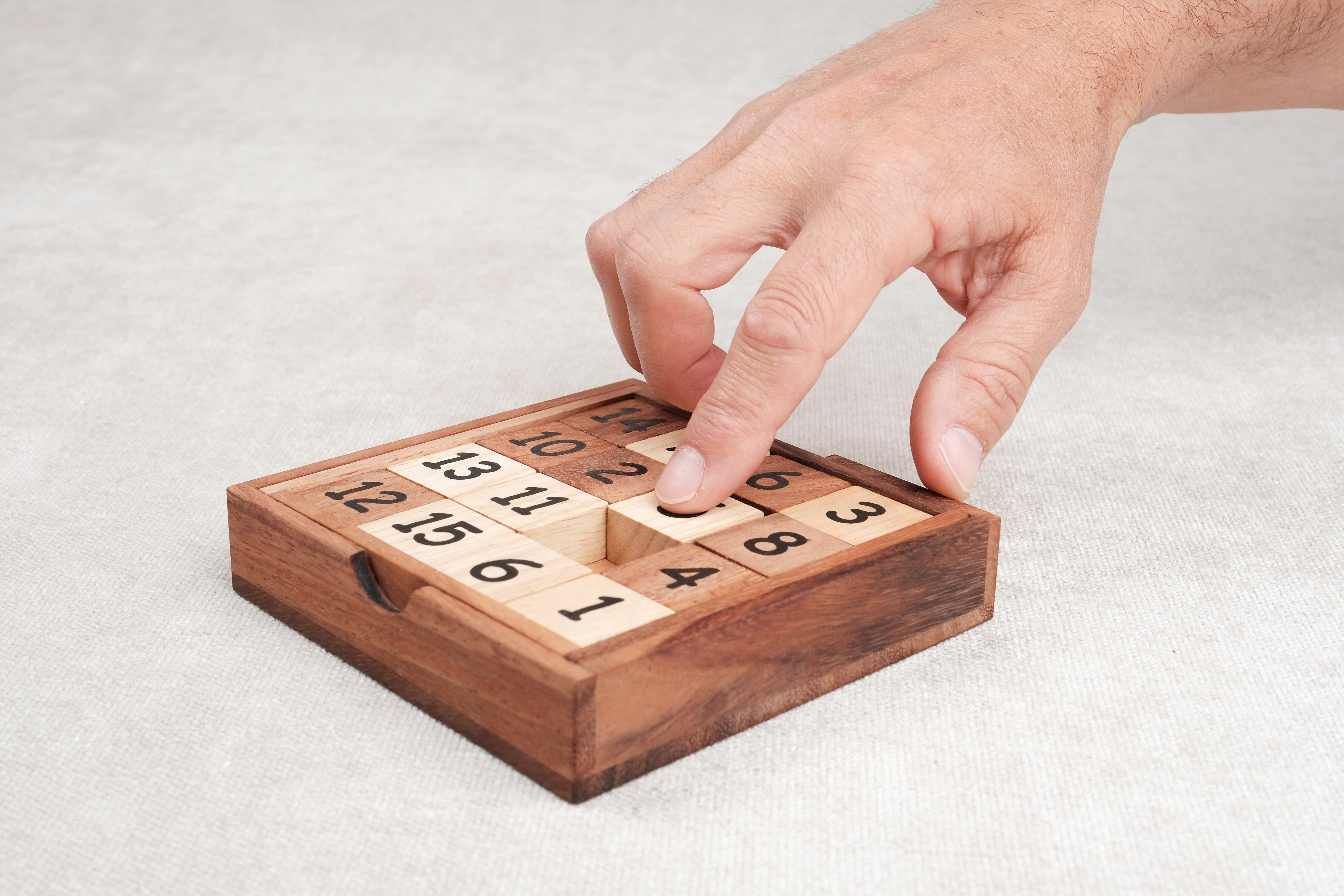 Main en train de déplacer une pièce du taquin