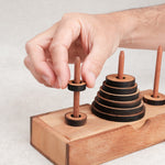 Jeu de logique La Tour de Hanoï en bois avec un joueur déplaçant un disque – Jeux Faugère