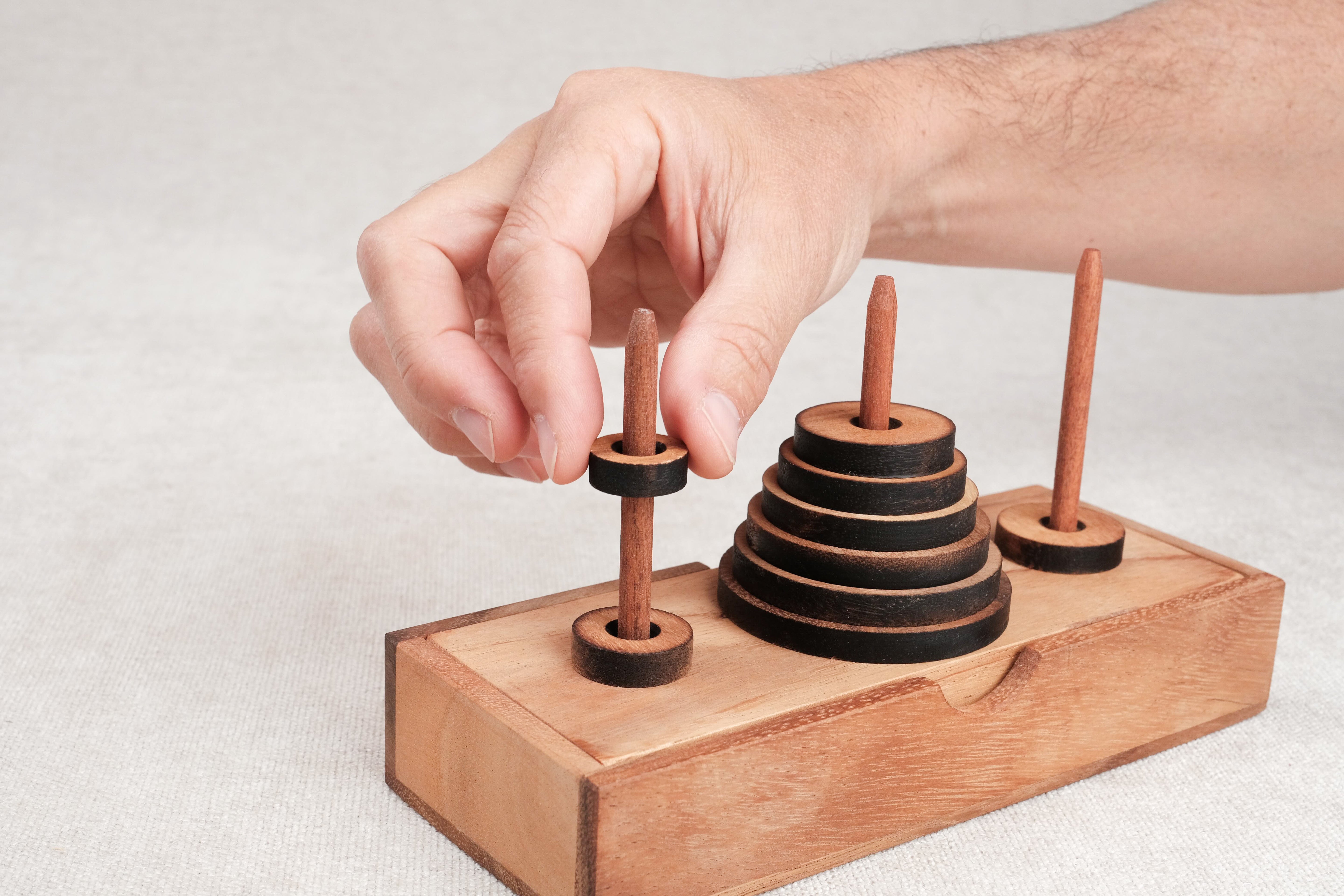 Jeu de logique La Tour de Hanoï en bois avec un joueur déplaçant un disque – Jeux Faugère
