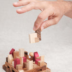 Main qui manipule une pièce du casse-tête La Cité Infernale en bois – Puzzle multi-combinaisons – Jeux Faugère