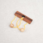 Casse-tête en bois Roméo & Juliette avec ficelle jaune et deux boules en bois.