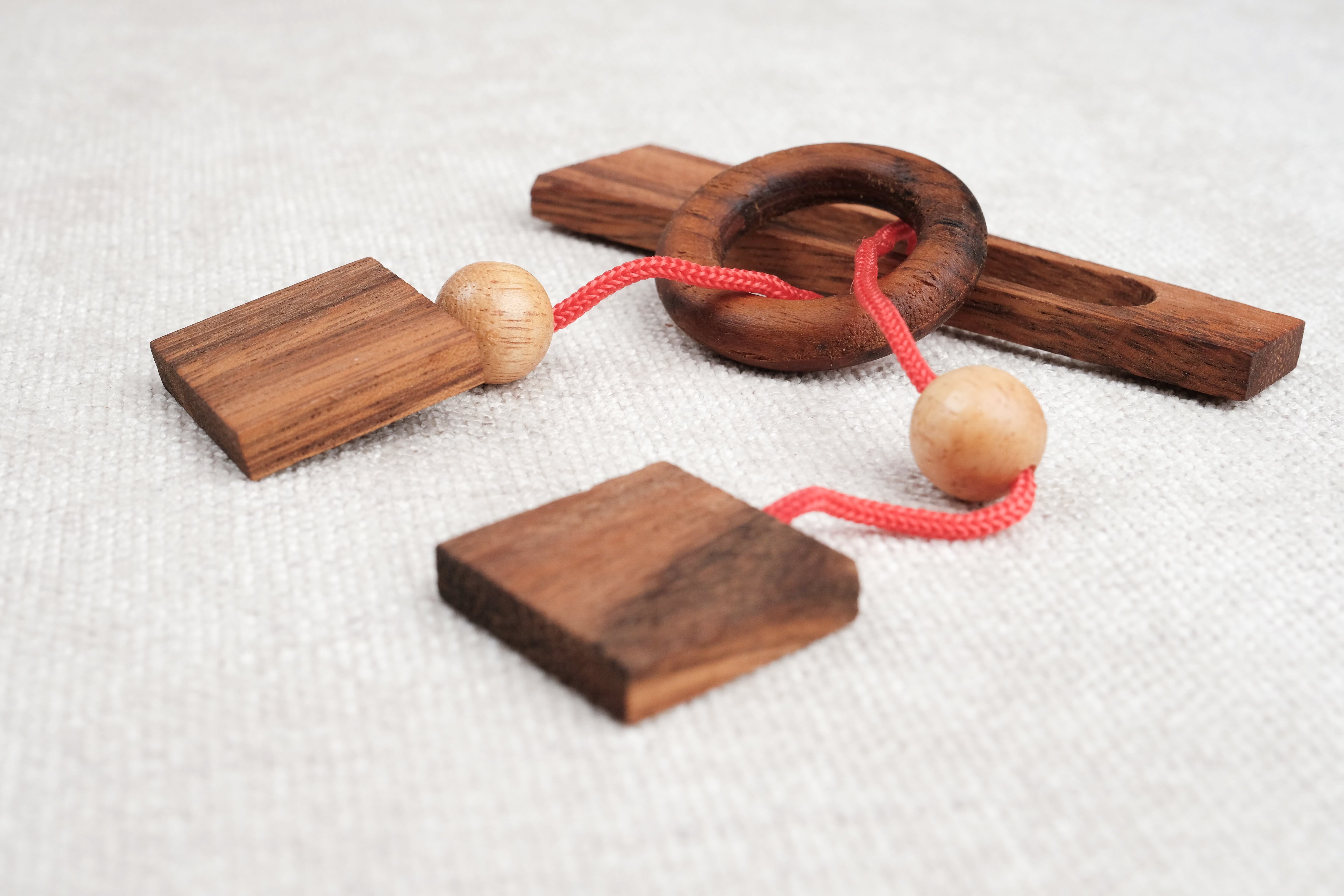 Gros plan sur le mini casse-tête Diapason en bois foncé et boules en hévéa – Jeux Faugère