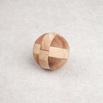 Ballon de foot en bois casse-tête posé fermé sur une surface claire.