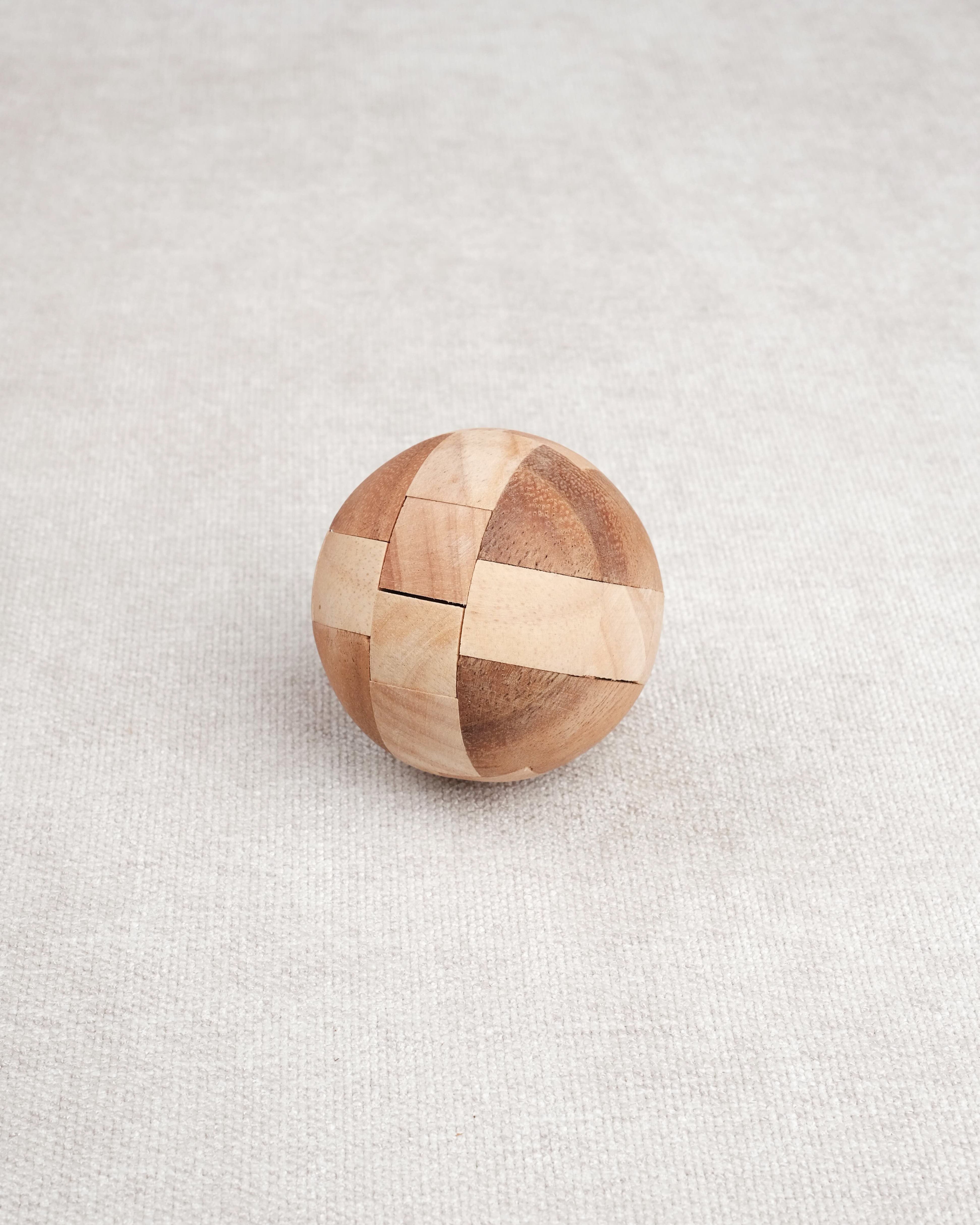 Ballon de foot en bois casse-tête posé fermé sur une surface claire.