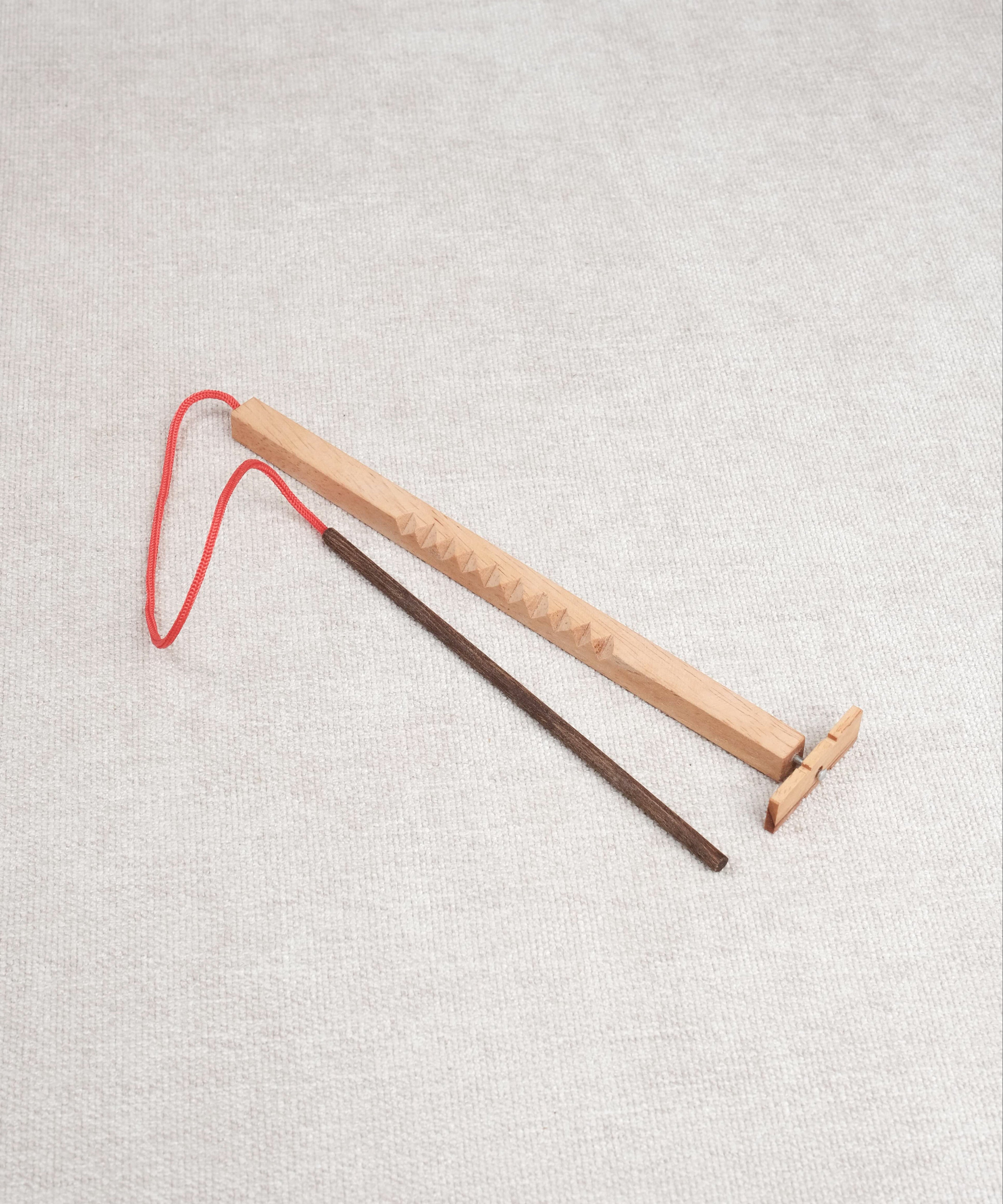 Casse-tête en bois Bozo-Bozo avec baguette et hélice reliée par une ficelle rouge.