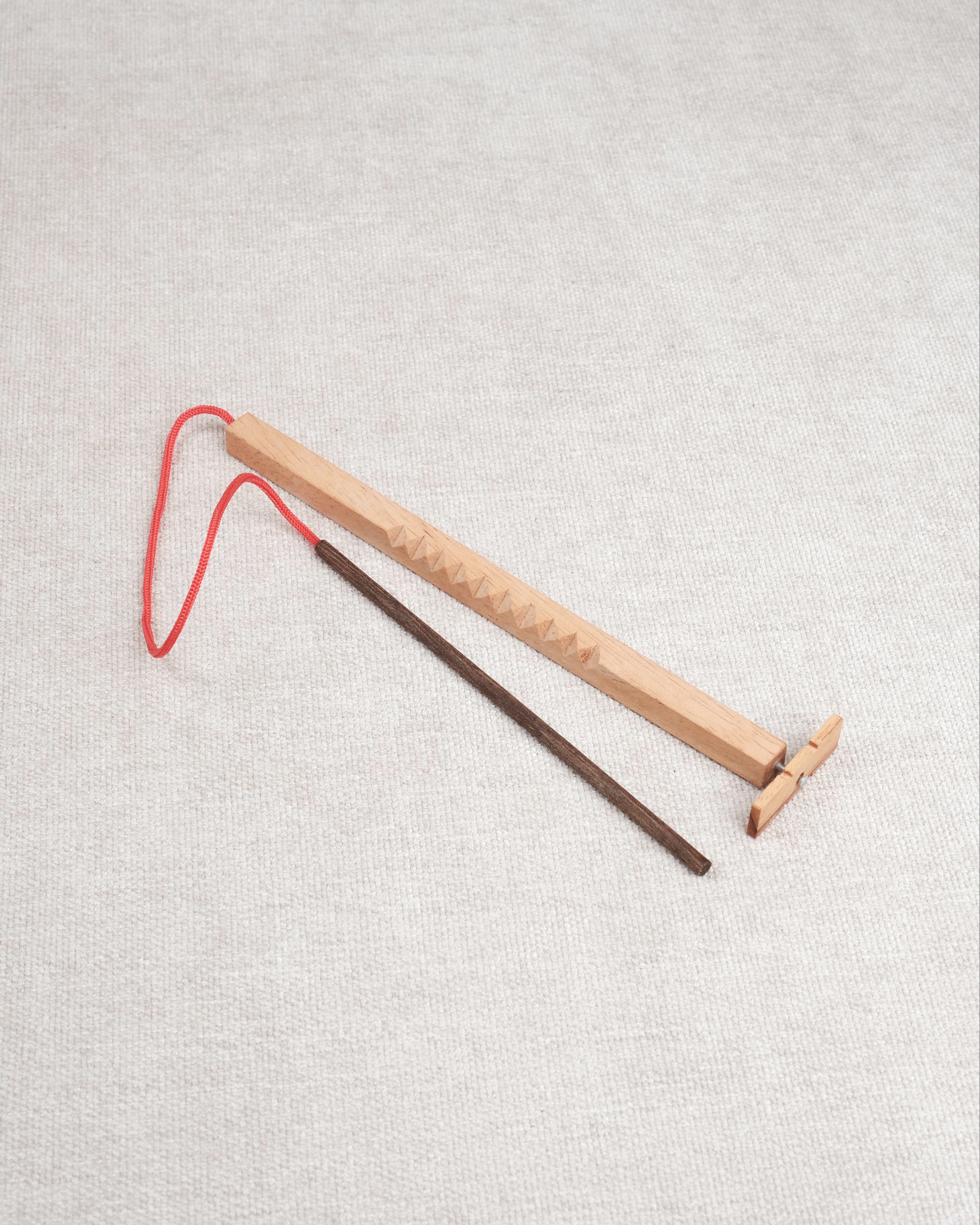 Casse-tête en bois Bozo-Bozo avec baguette et hélice reliée par une ficelle rouge.