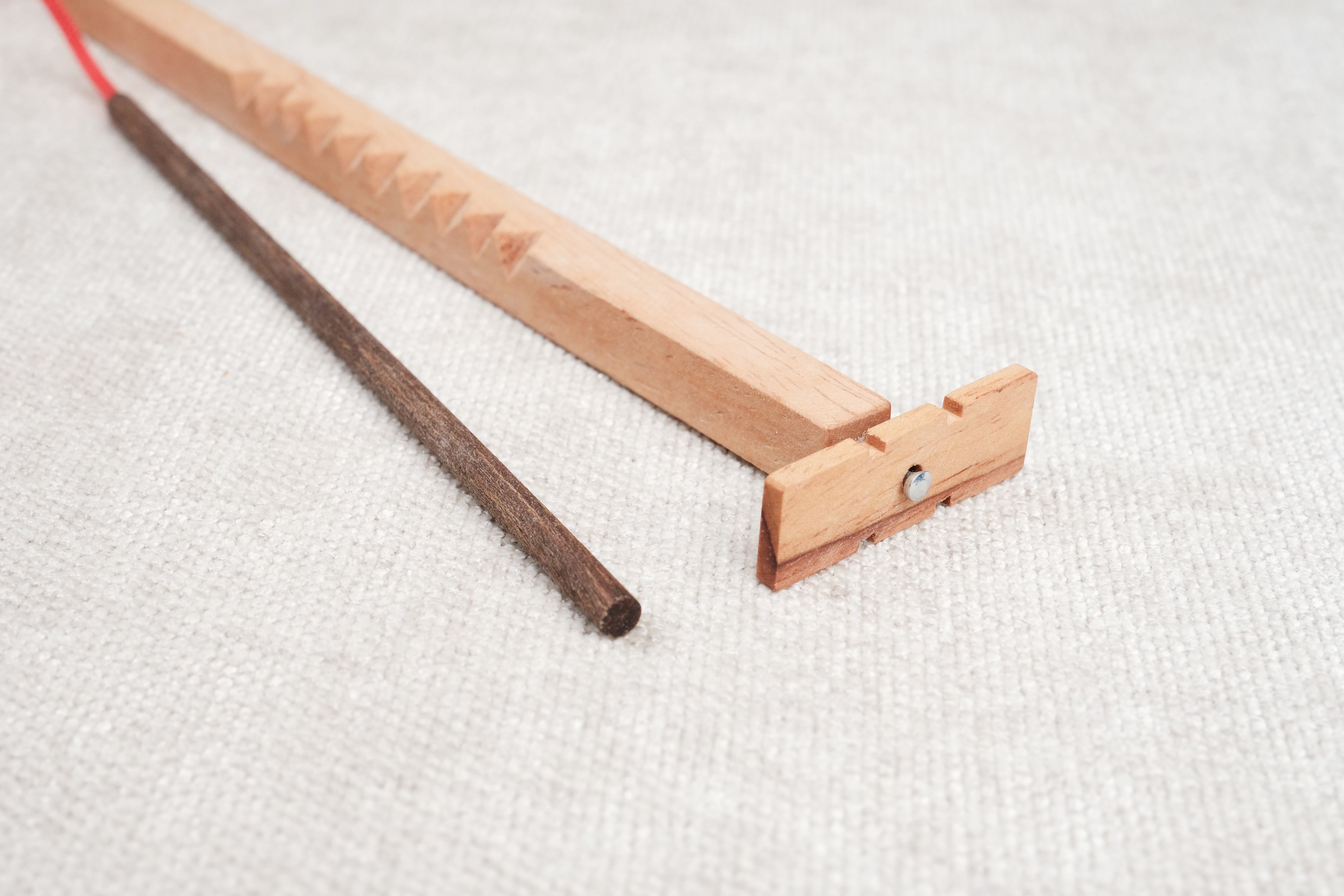 Détail du casse-tête Bozo-Bozo montrant l’hélice en bois et la baguette foncée.