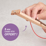 Main en train de jouer au Bozo Bozo, mini casse-tête avec ficelle rouge