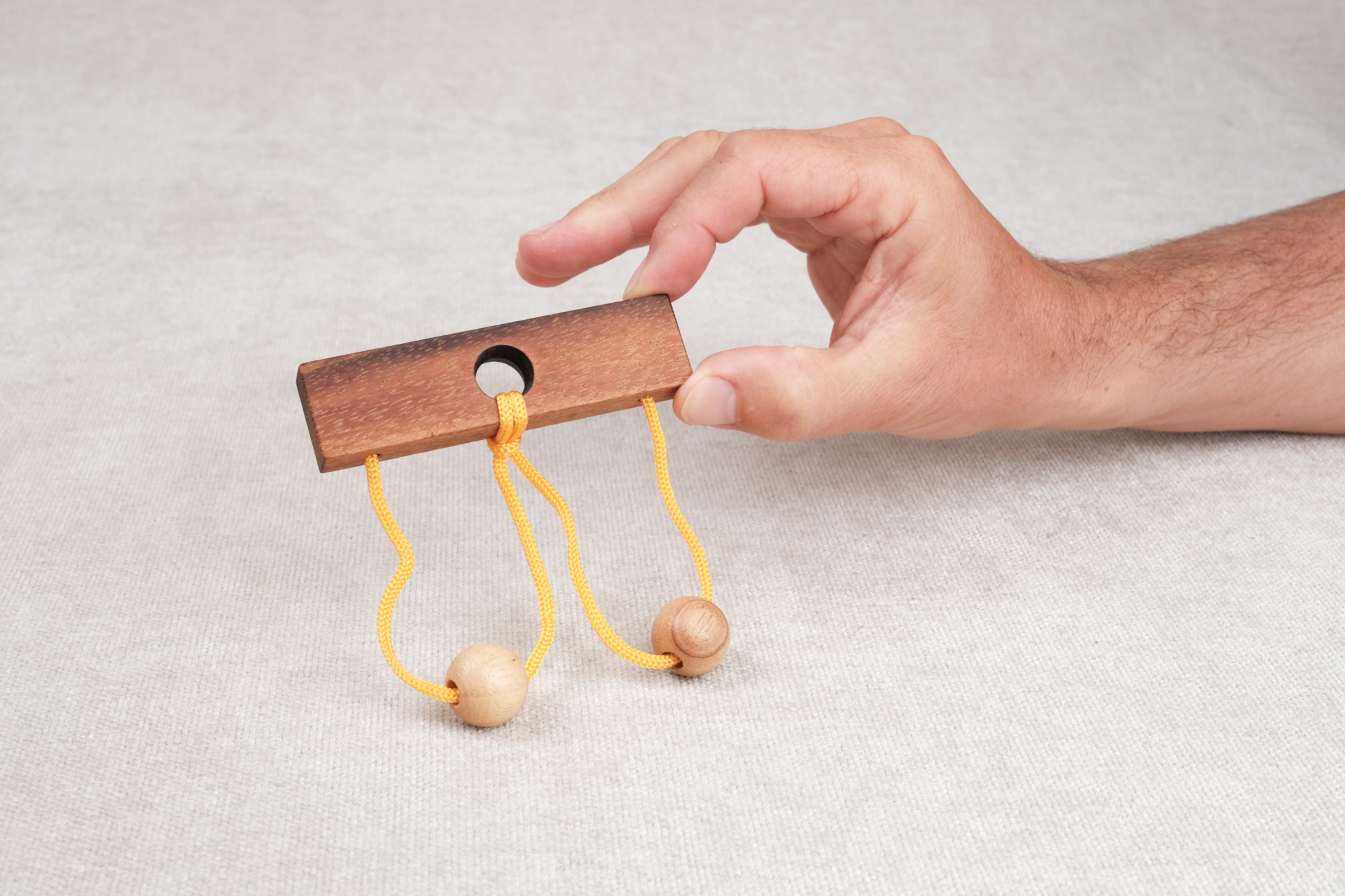 Main tenant le casse-tête ficelle Roméo & Juliette en bois.