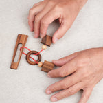 Joueur manipulant le casse-tête ficelle Diapason pour tenter de libérer l’anneau – Jeux Faugère