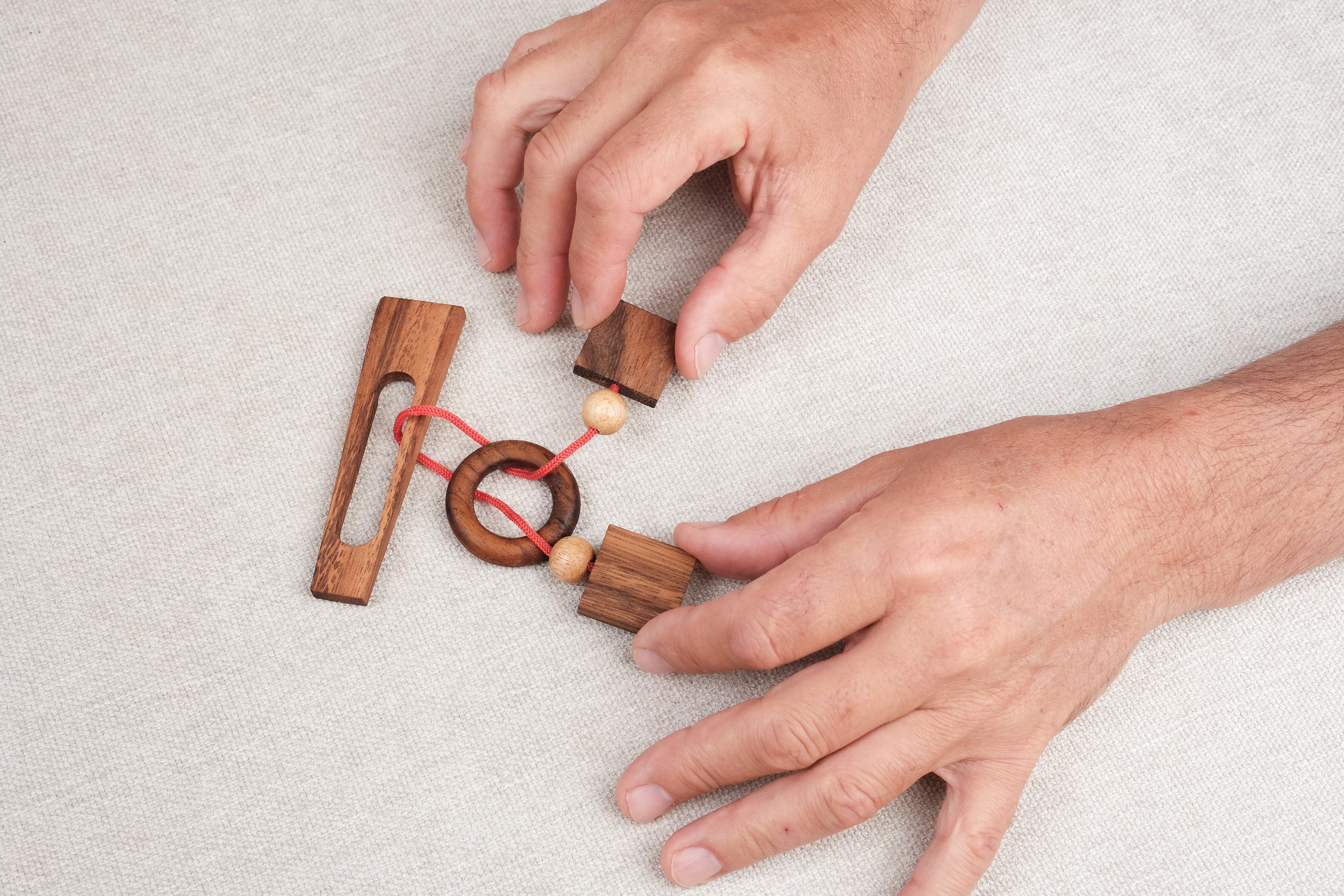 Joueur manipulant le casse-tête ficelle Diapason pour tenter de libérer l’anneau – Jeux Faugère
