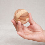 Ballon de foot en bois tenu dans une main, vue de taille compacte.