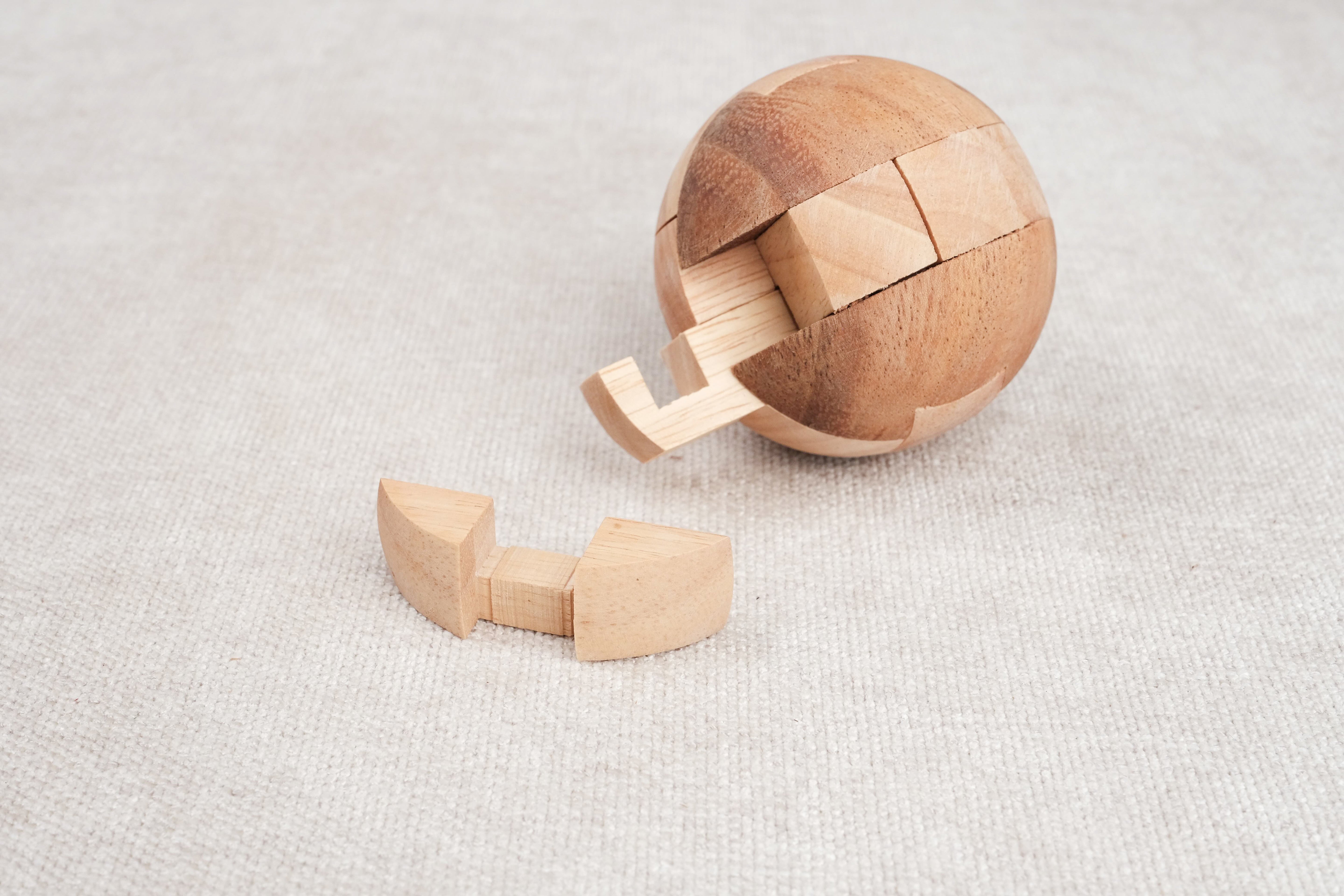 Ballon de foot en bois ouvert avec une pièce retirée, puzzle en cours de démontage.