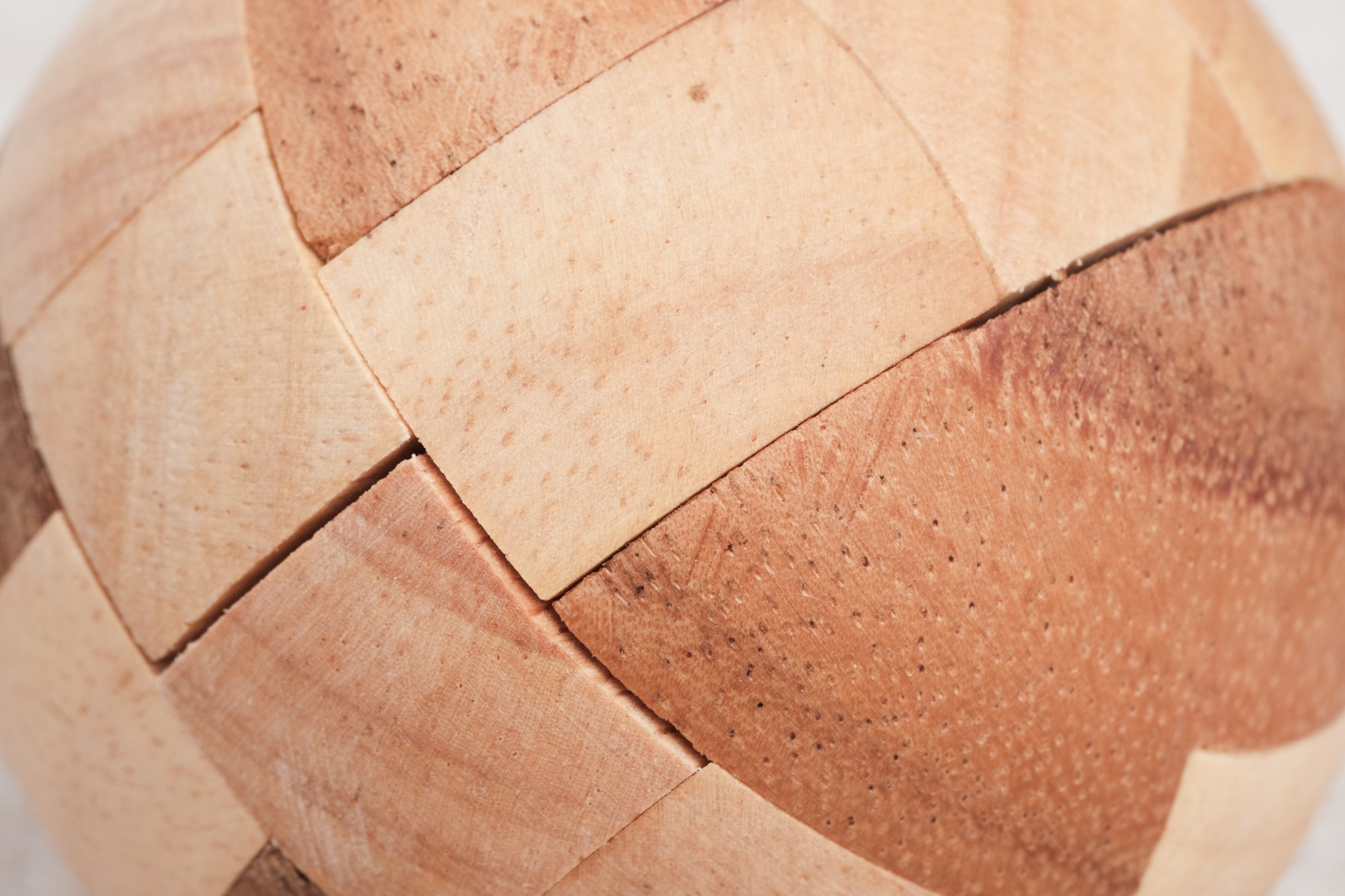 Gros plan sur le ballon de foot en bois montrant le détail des pièces imbriquées.