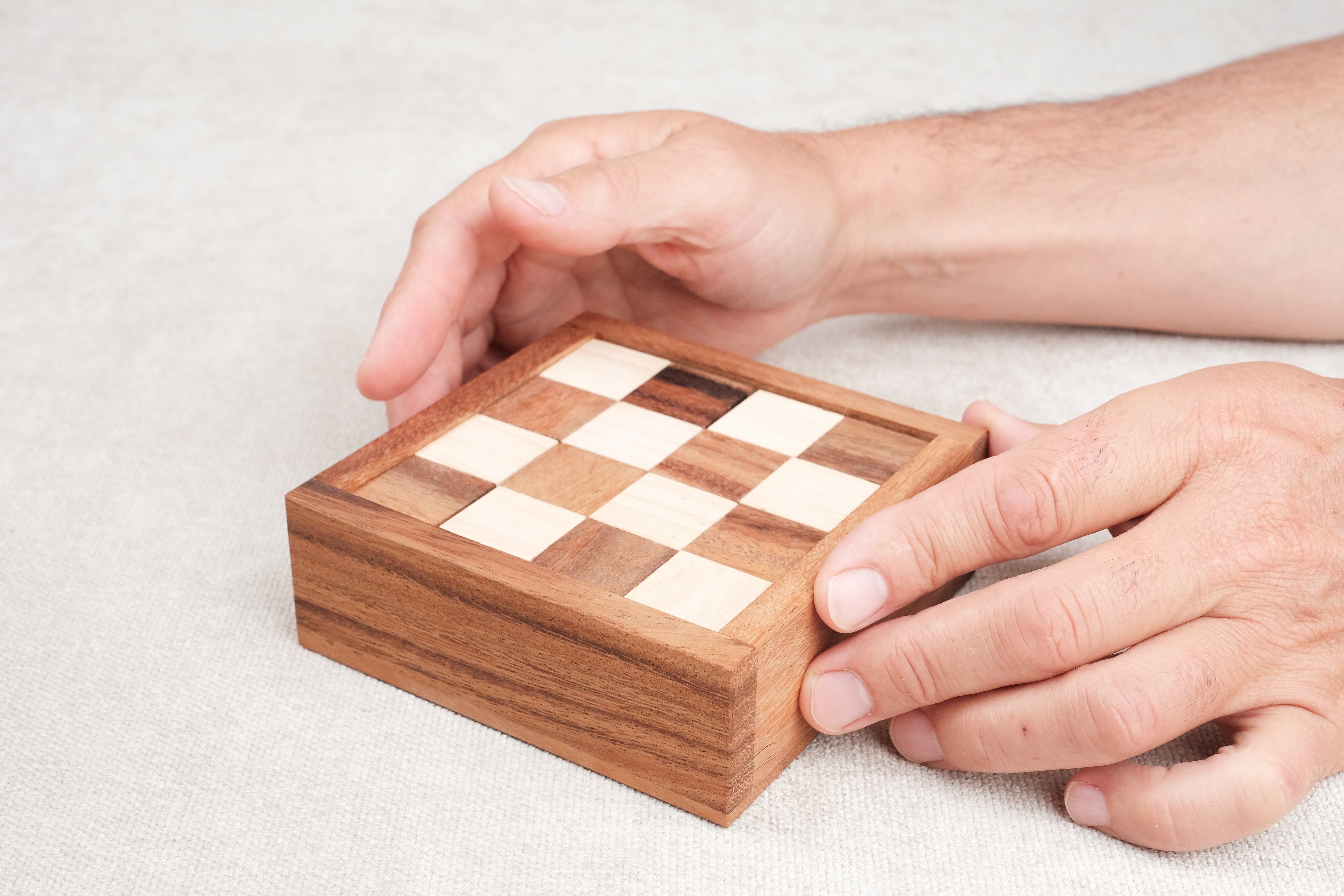 Casse-tête Le Damier en bois – manipulation du coffret par une main