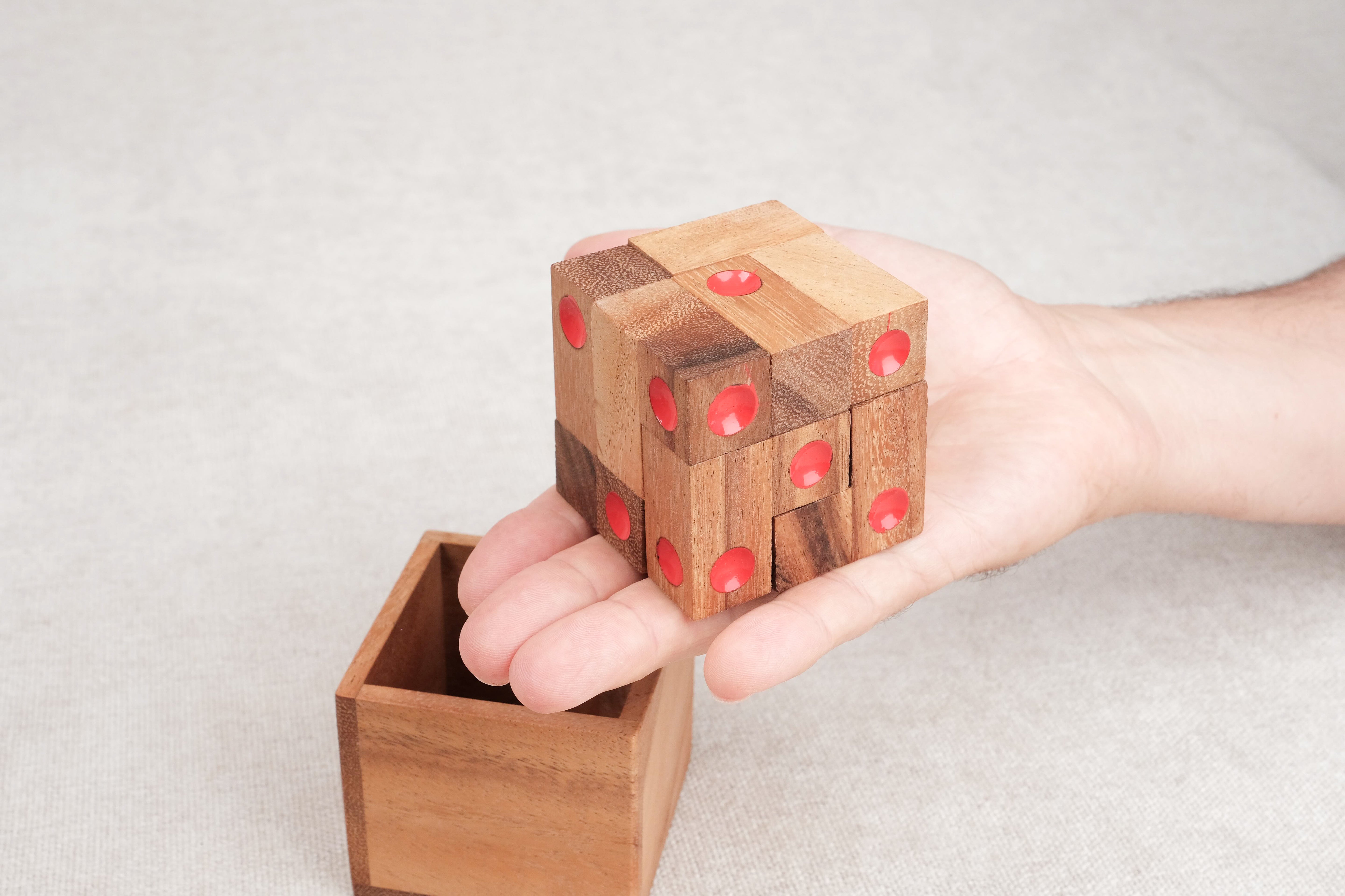 Casse-tête Dé enfermé en bois tenu en main au-dessus de son coffret – Jeux Faugère