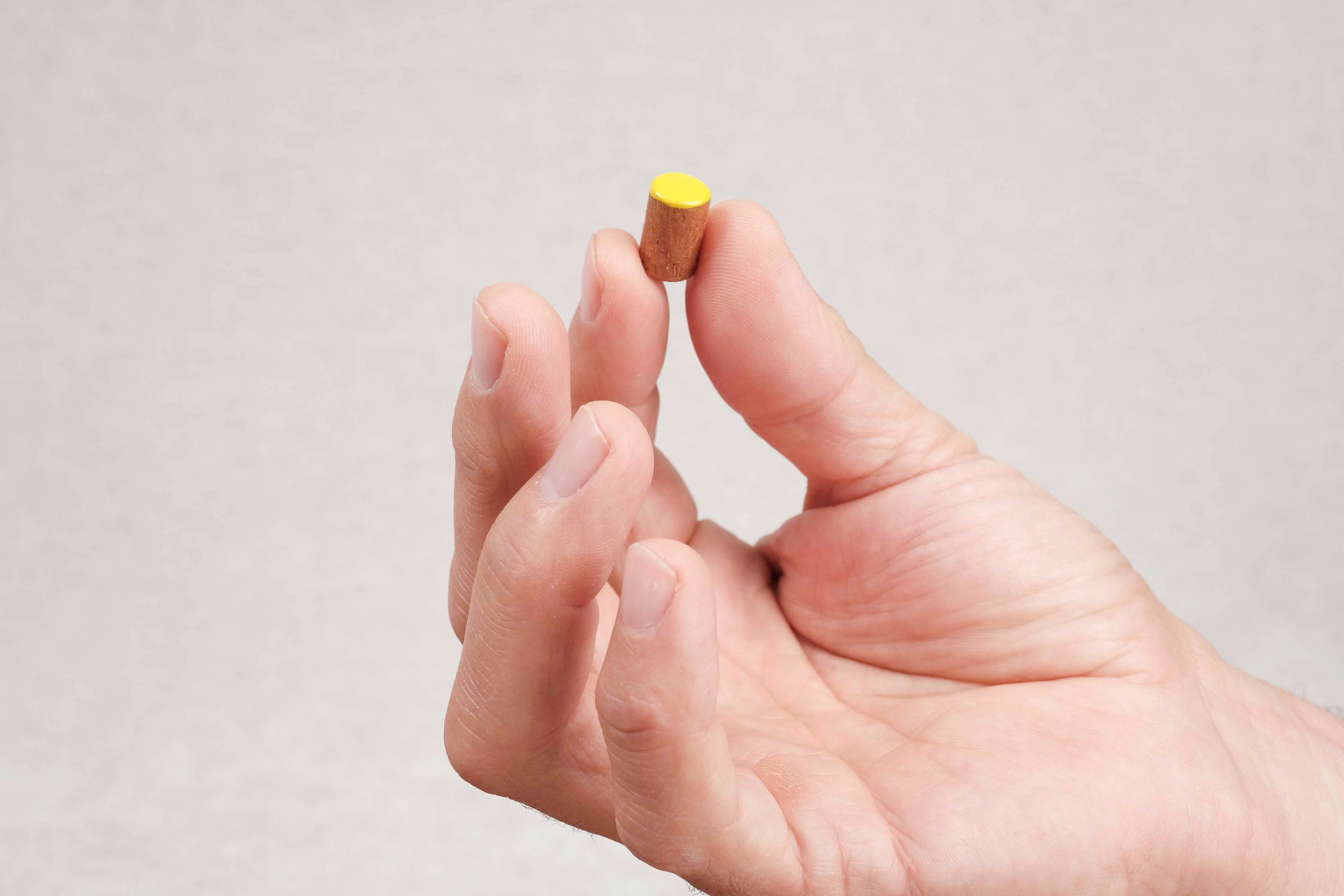 Un pion jaune tenu entre deux doigts