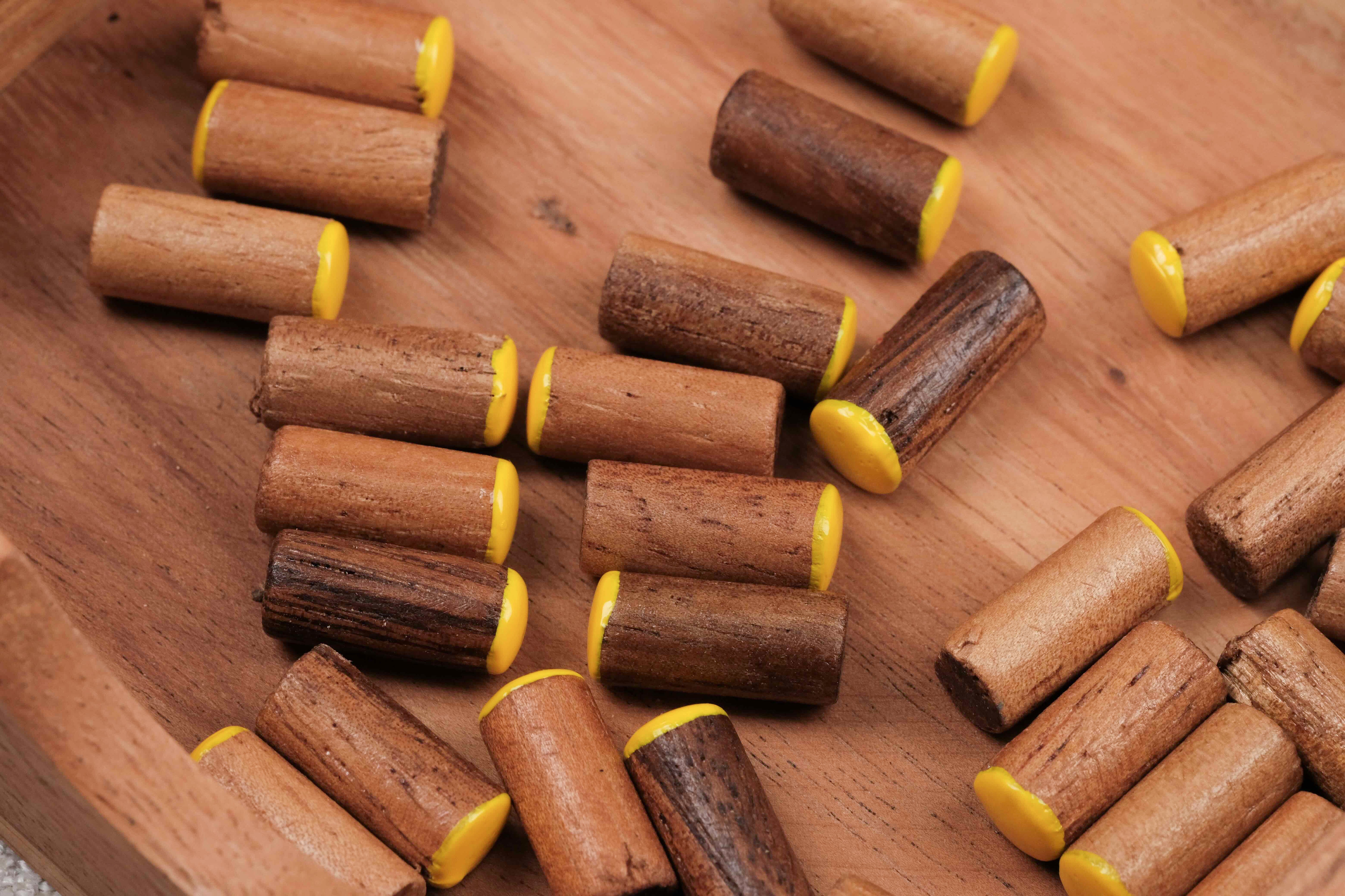 Zoom sur plusieurs pions jaunes en bois dans le coffret