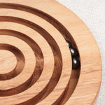 Gros plan sur une bille métallique en mouvement dans les rainures du Labyrinthe en bois – Jeux Faugère