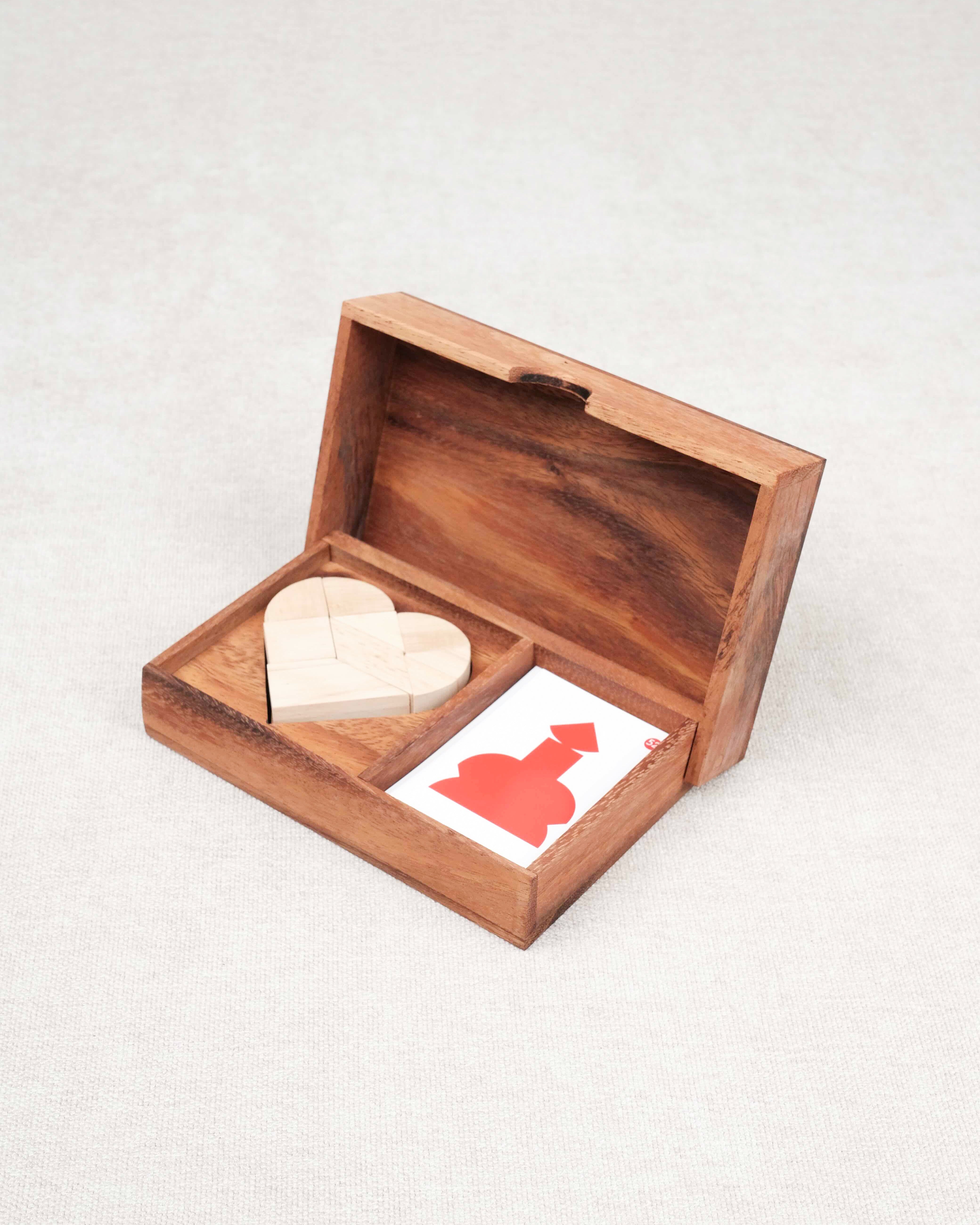 Coffret en bois ouvert contenant un tangram cœur et des cartes défis – Double Tangram Cœur Jeux Faugère