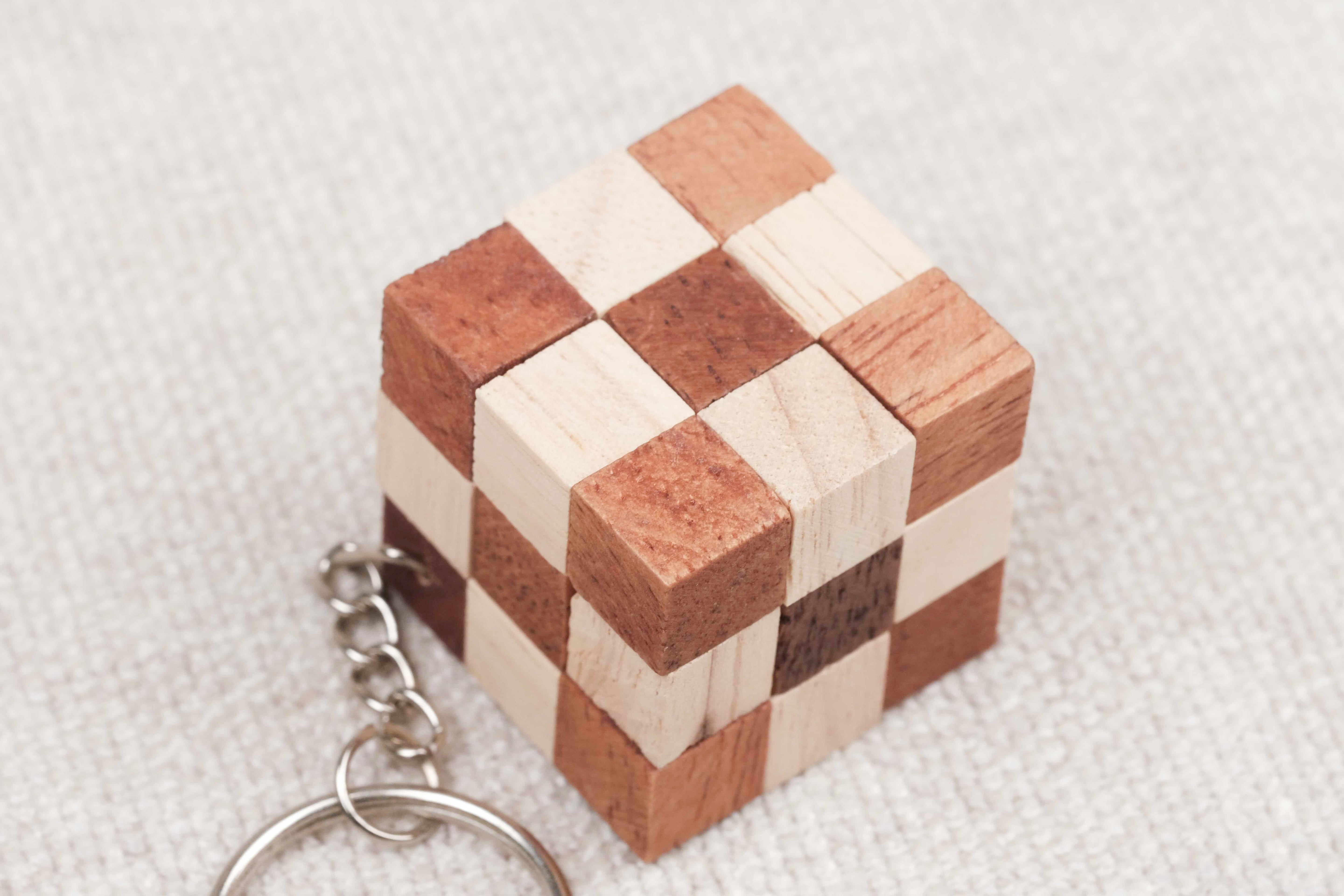 Gros plan du mini cube serpent en bois, motif damier clair et foncé.