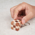 Main manipulant le mini cube serpent en bois porte-clés.