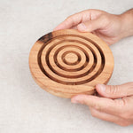 Deux mains tenant le jeu d’adresse Labyrinthe en bois circulaire – Jeux Faugère