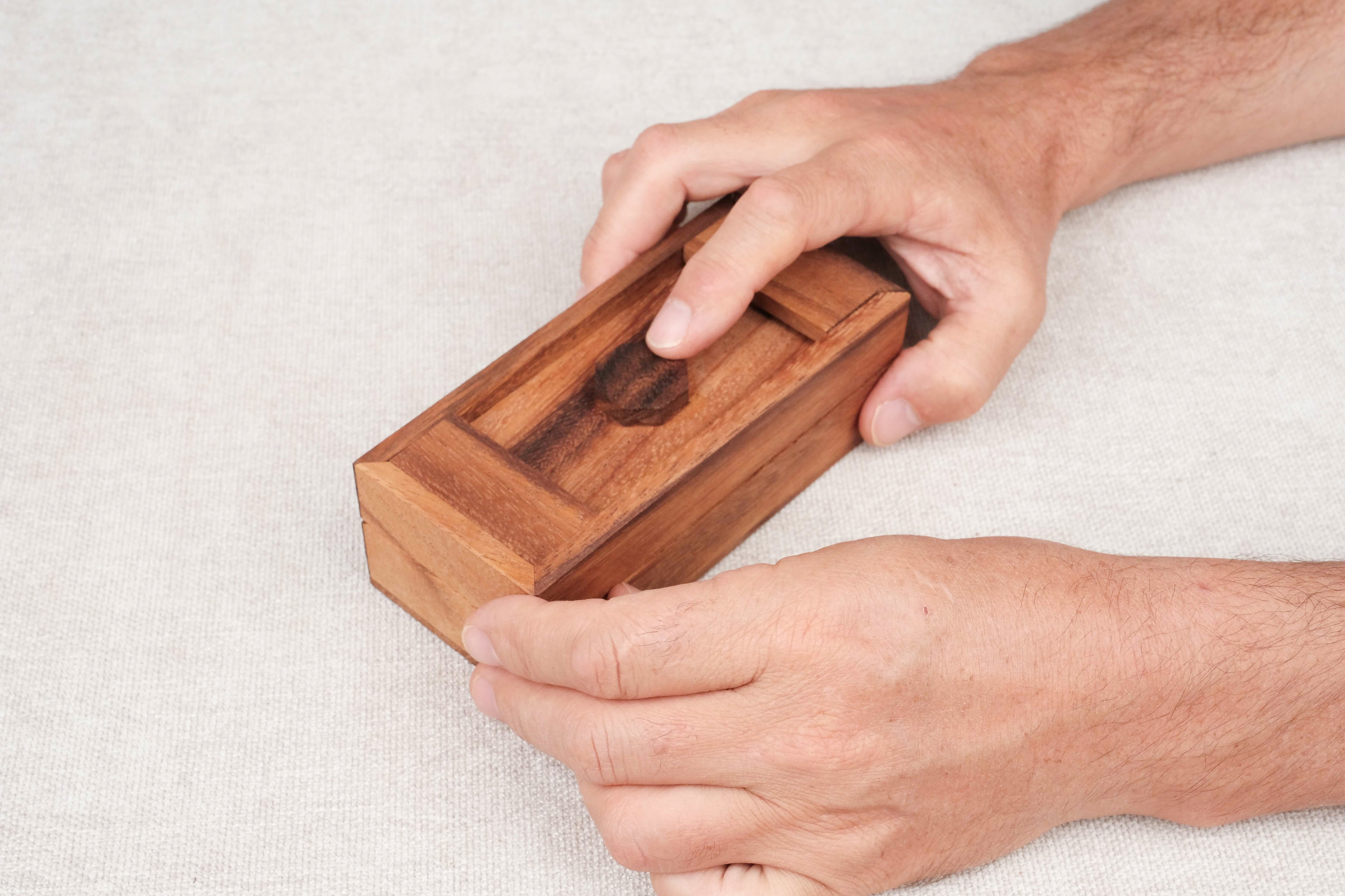 Main en train de d'essayer d'ouvrir la boîte secrète casse-tête en bois