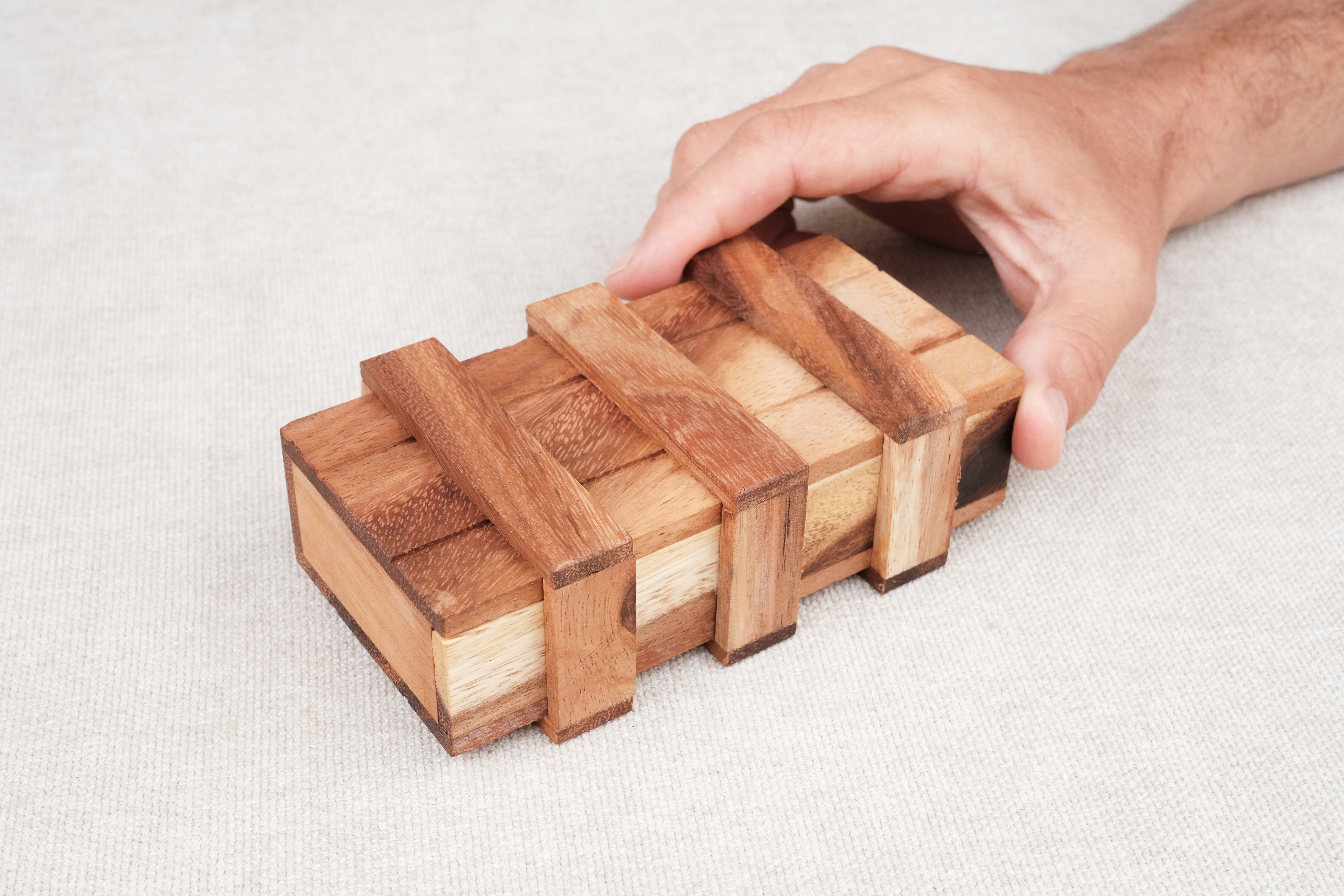 Joueur tentant d’ouvrir la Double Boîte Secrète en bois – Puzzle casse-tête Jeux Faugère