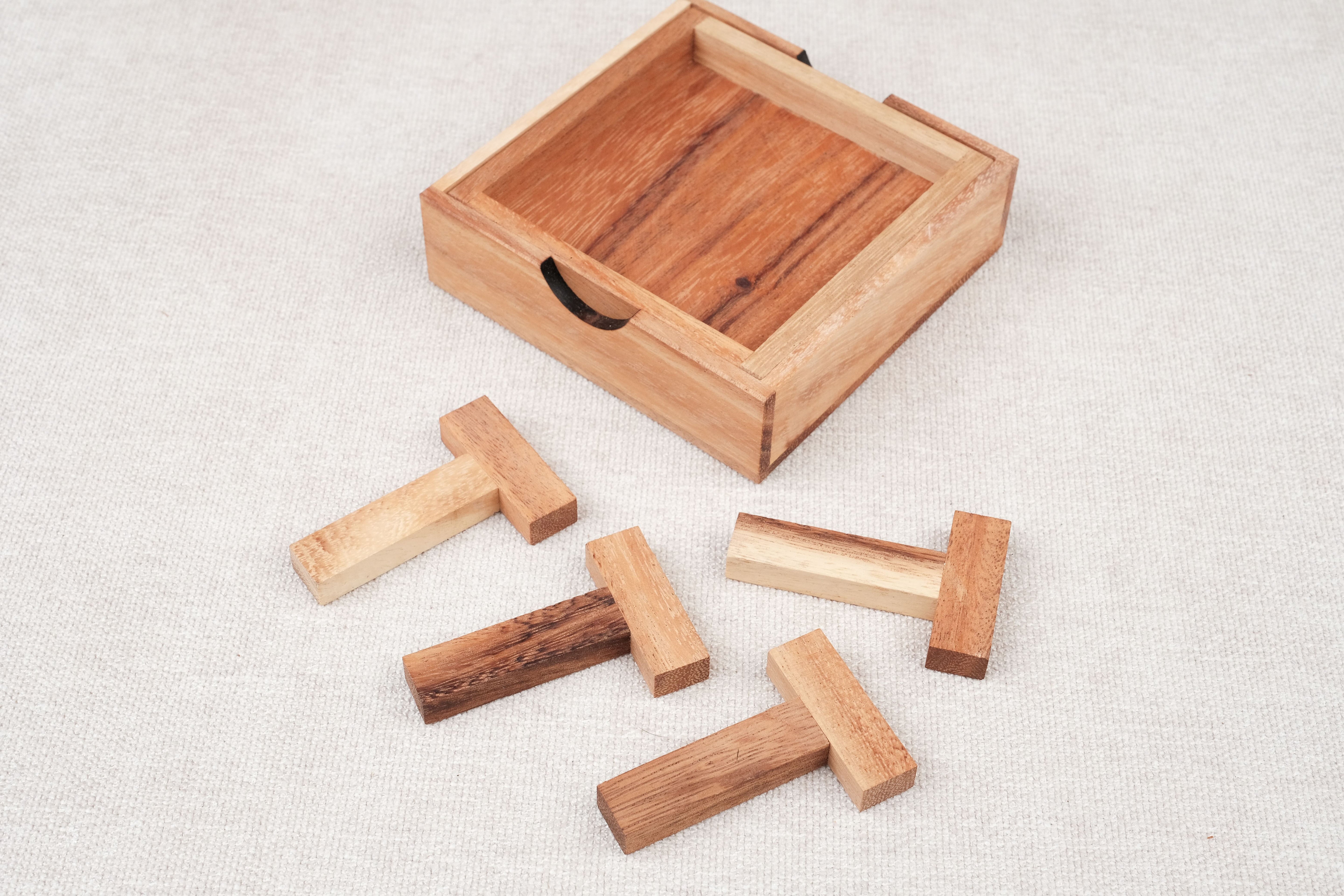 Pièces du casse-tête Les 4 T disposées à côté du coffret en bois