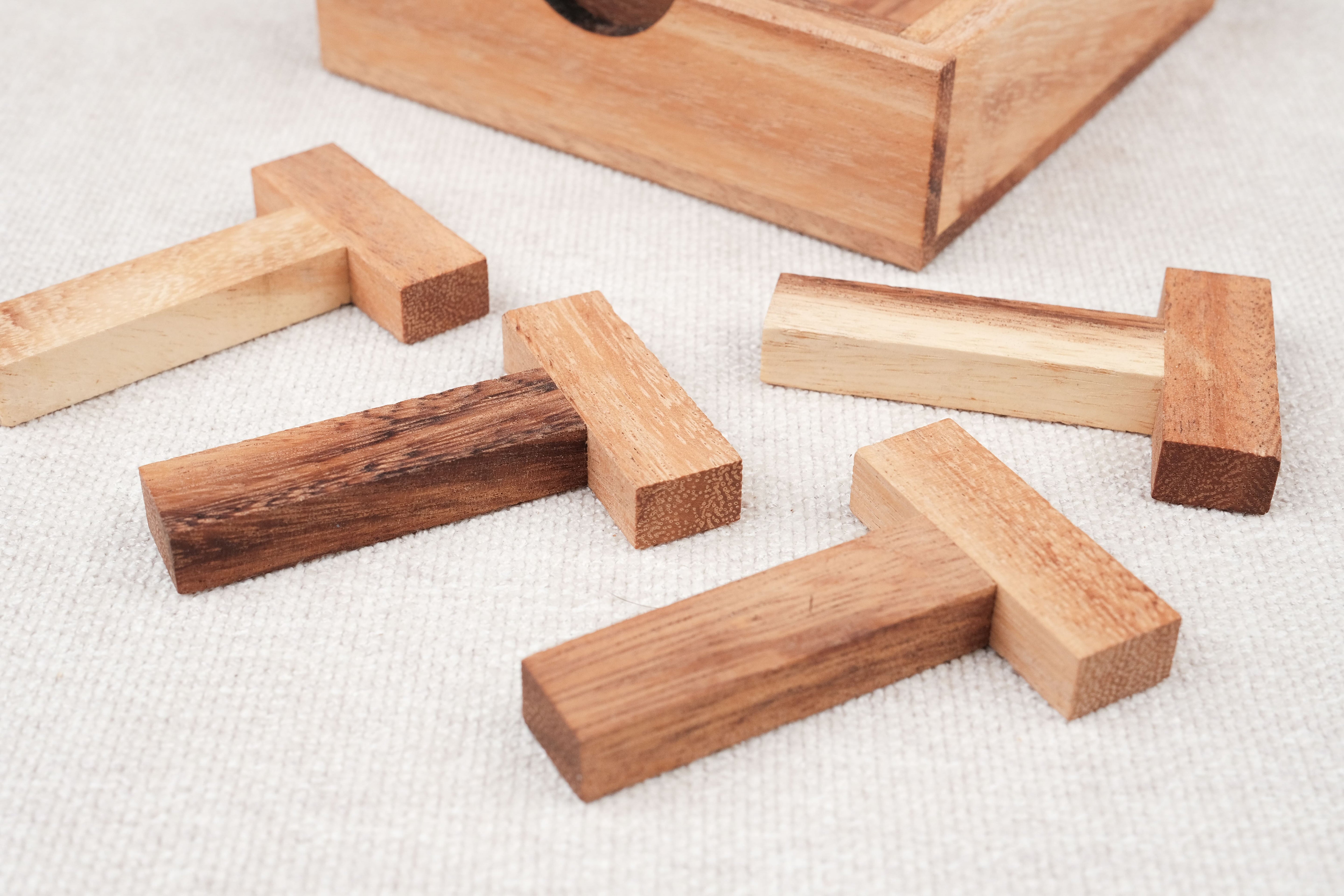 Gros plan sur les pièces en bois clair et foncé du casse-tête Les 4 T