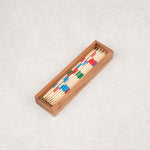 Coffret en bois d’acacia contenant un jeu de Mikado en baguettes colorées.