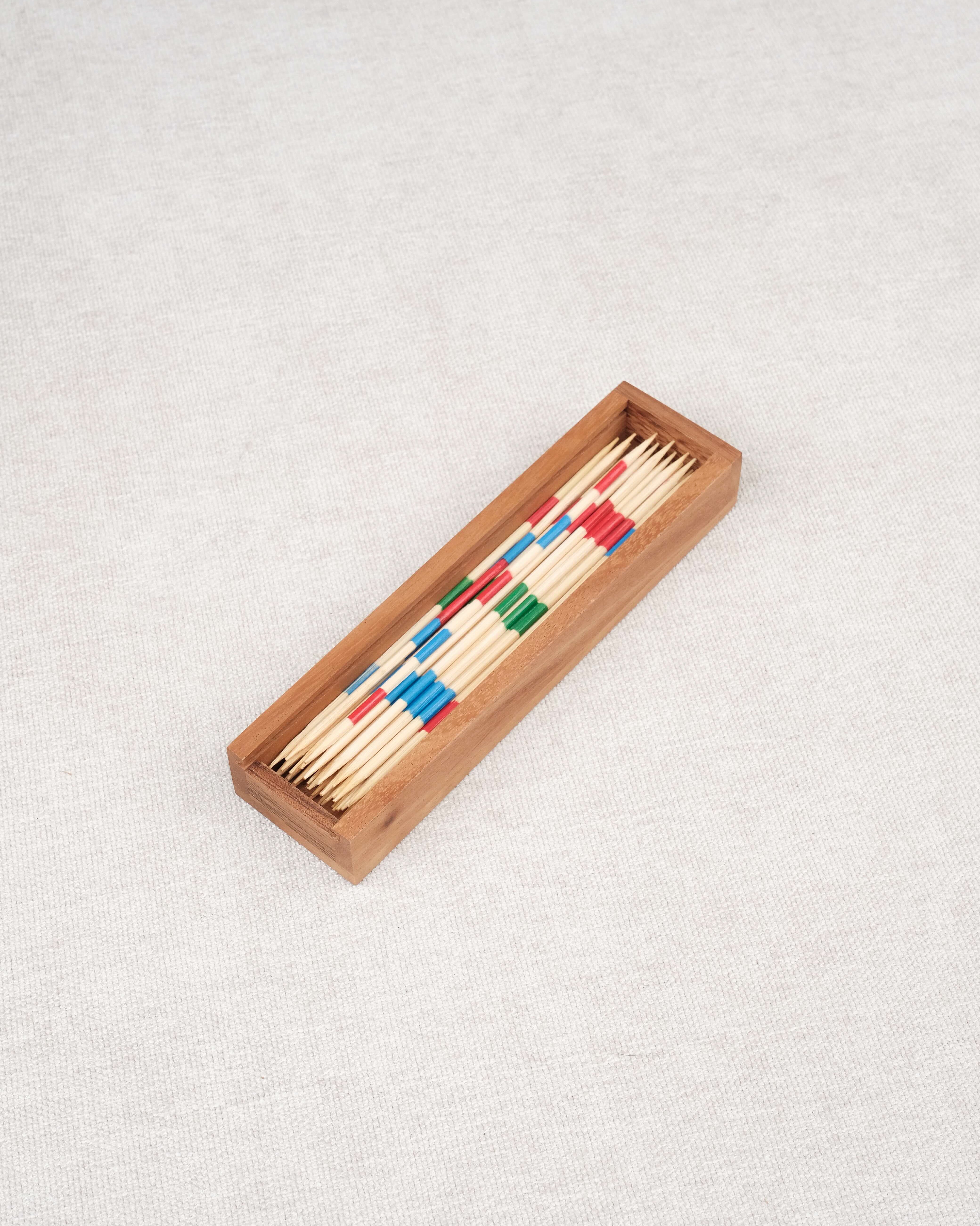 Coffret en bois d’acacia contenant un jeu de Mikado en baguettes colorées.