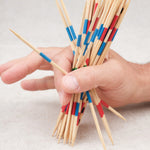 Main d’un joueur saisissant les mikados pour débuter la partie.