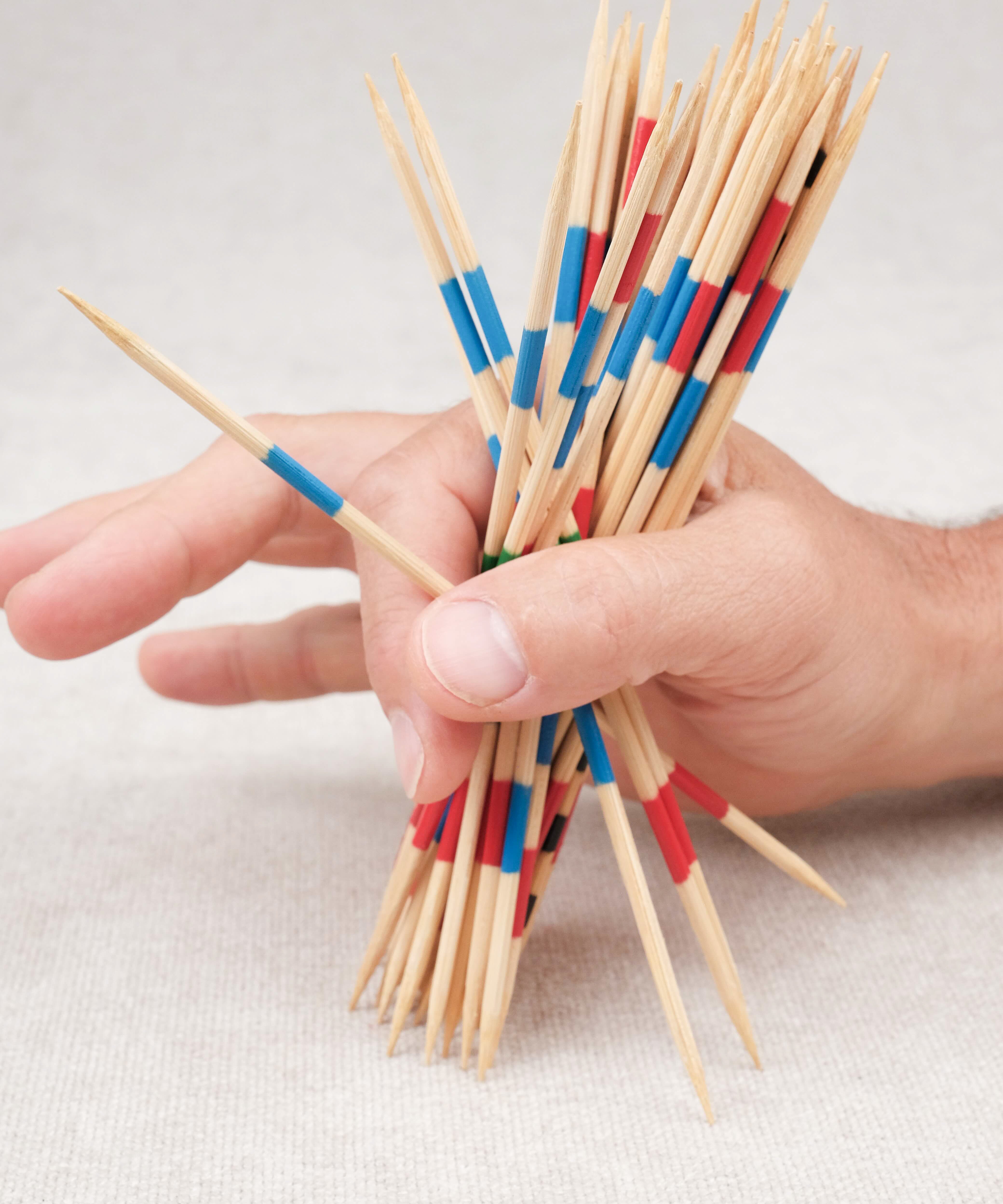 Main d’un joueur saisissant les mikados pour débuter la partie.