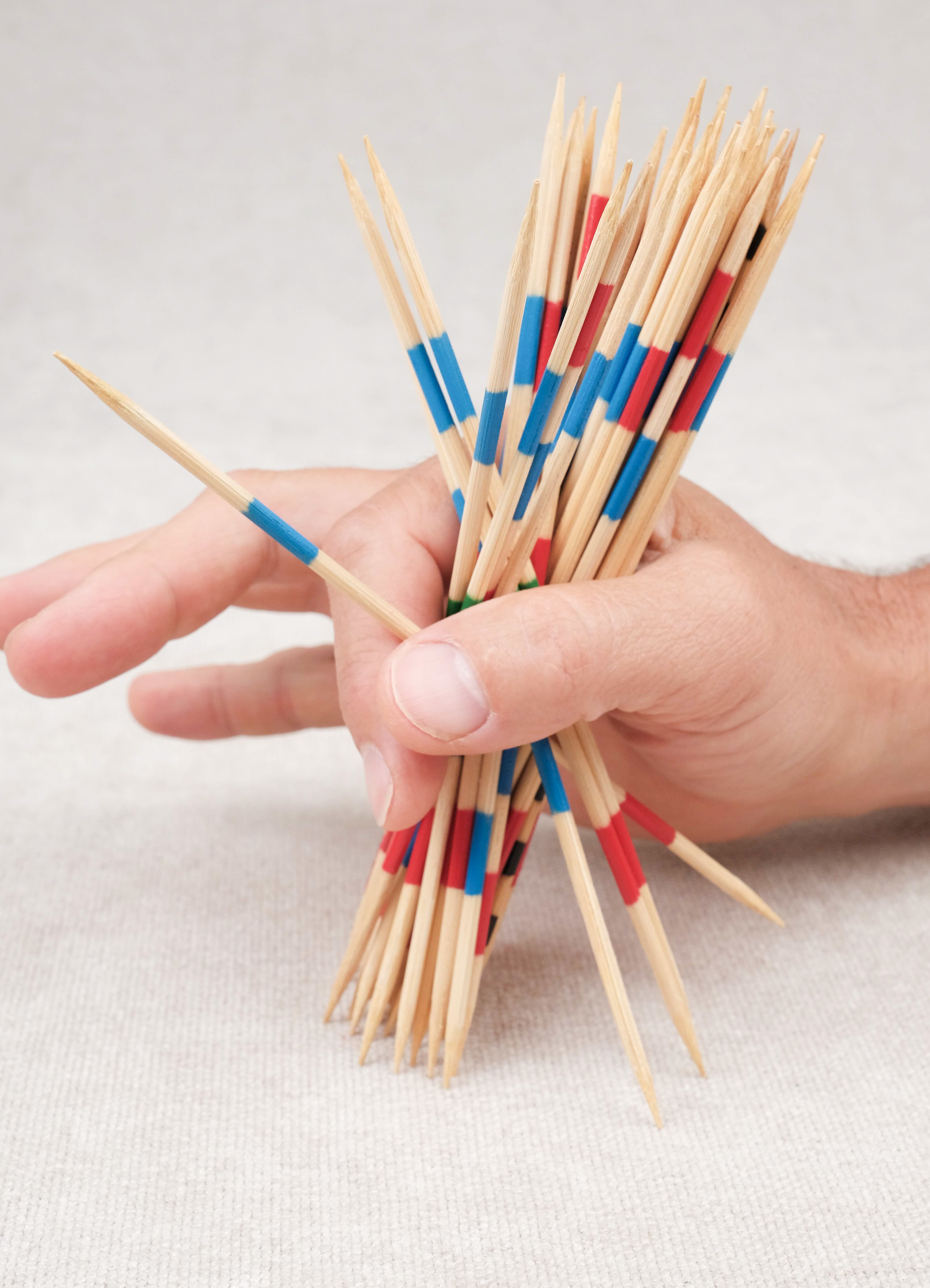 Main d’un joueur saisissant les mikados pour débuter la partie.