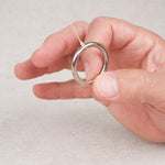 Gros plan sur un anneau métallique du Jeu de l’anneau tenu entre les doigts