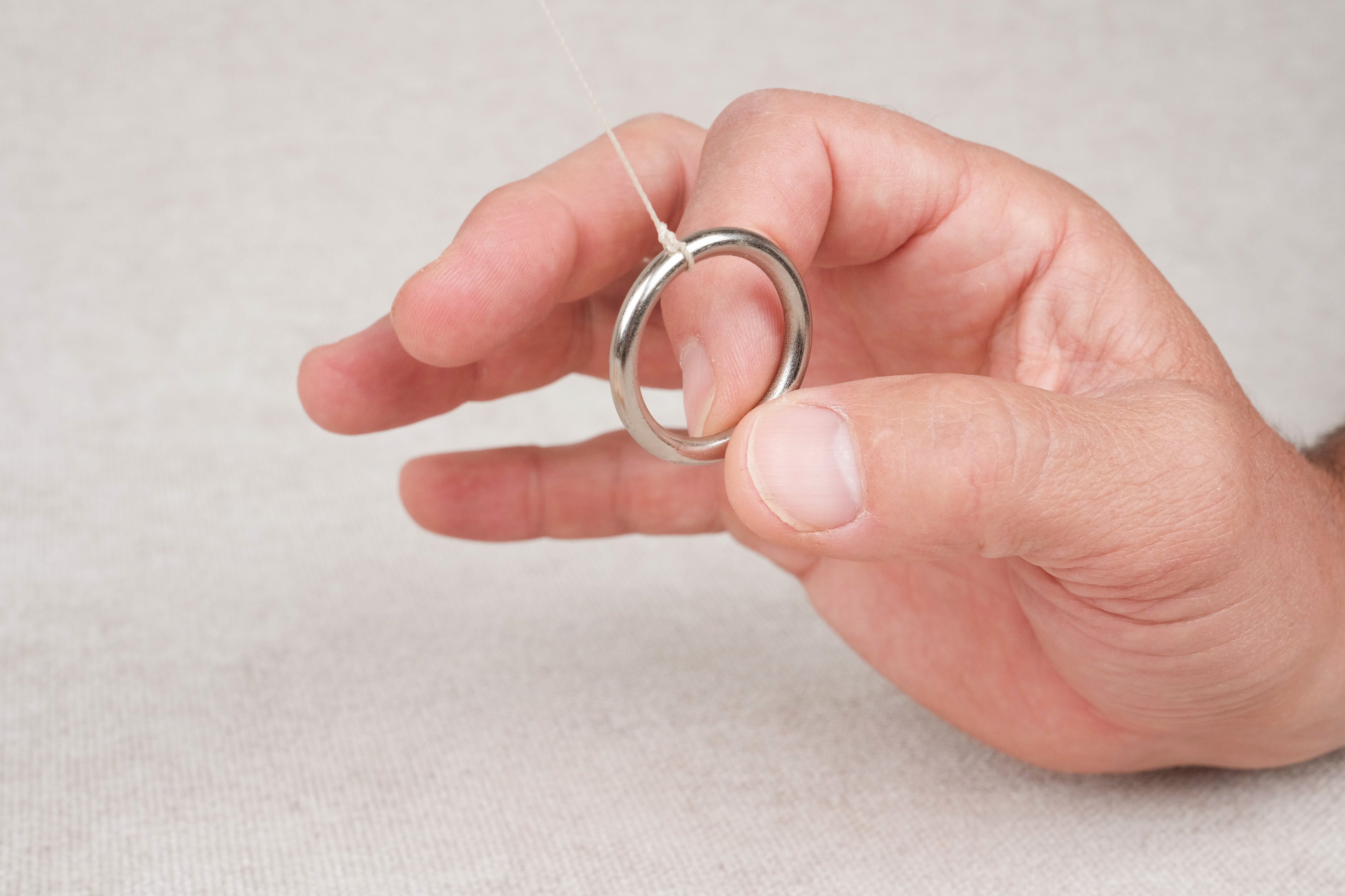 Gros plan sur un anneau métallique du Jeu de l’anneau tenu entre les doigts