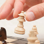 Main déplaçant un pion d’échecs blanc magnétique sur plateau marron