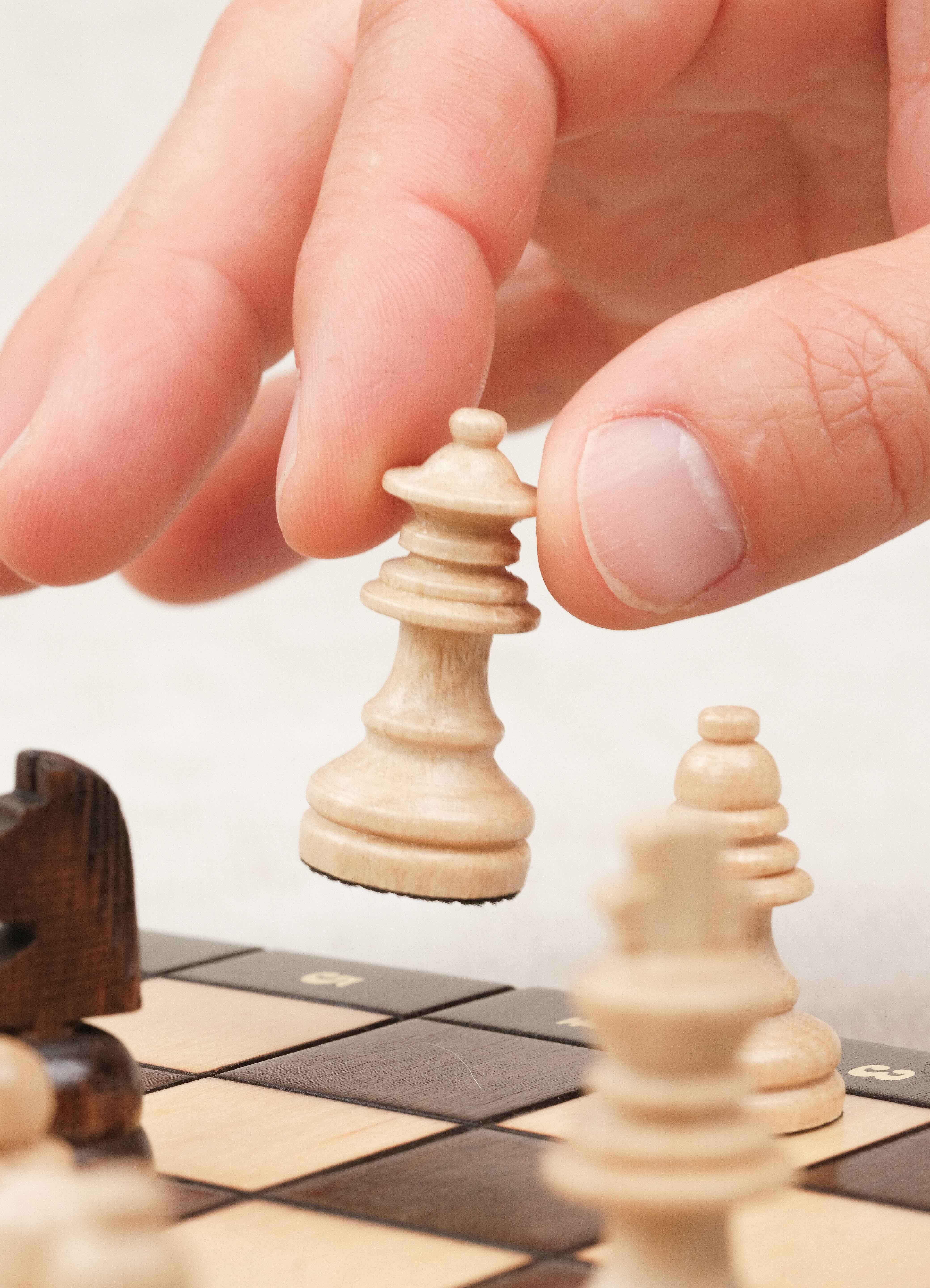 Main déplaçant un pion d’échecs blanc magnétique sur plateau marron