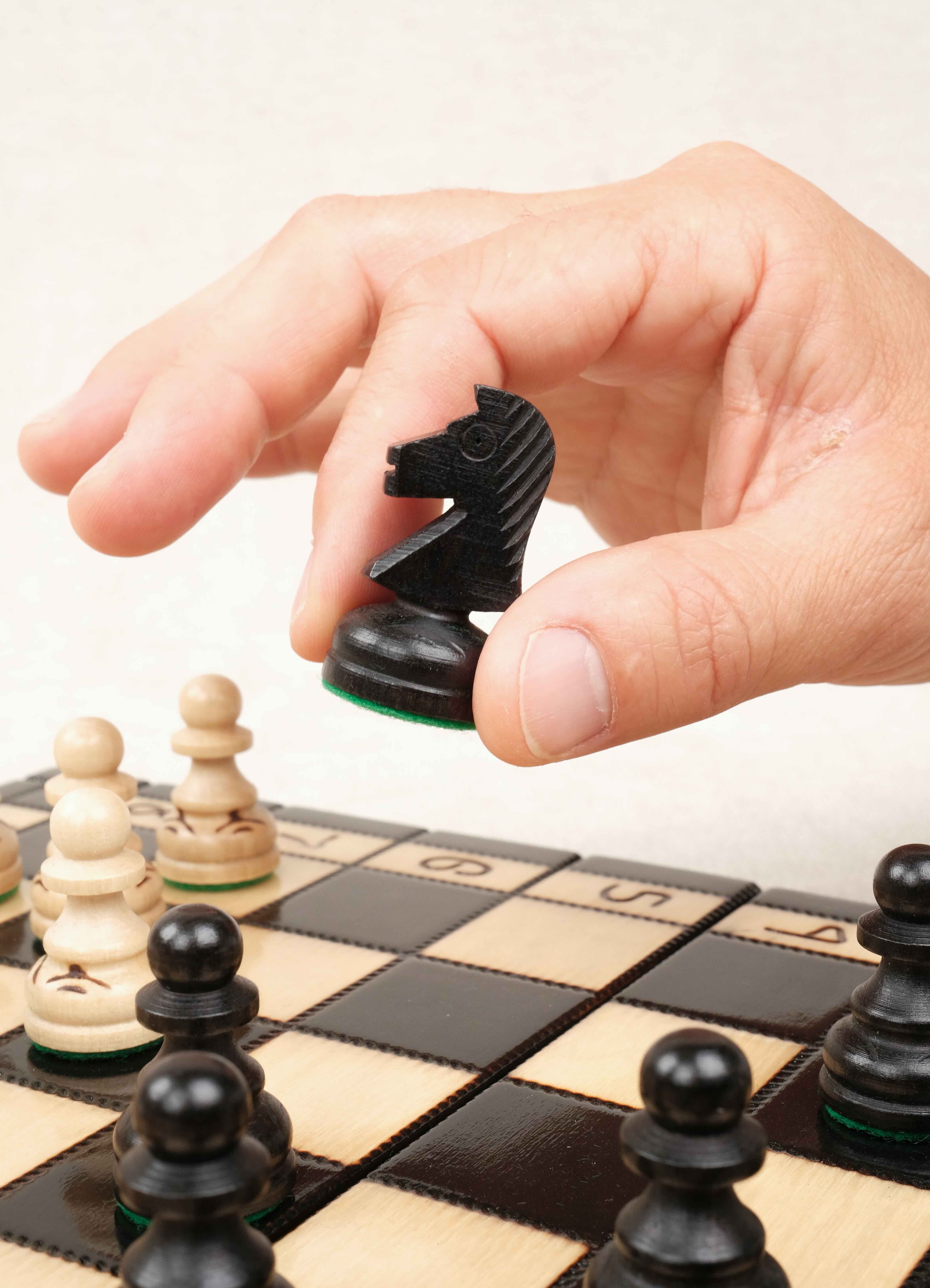 Main en train de déplacer une pièce d’échecs noire sur le plateau
