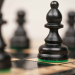 Détail d’une pièce d’échecs noire sculptée en bois sur le plateau