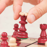 Main en train de déplacer une pièce d’échecs rouge sur le plateau